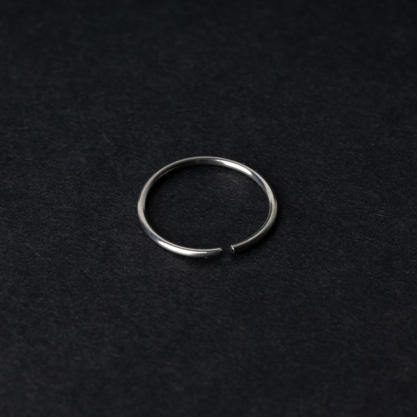A single thin silver seamless hoop with a polished finish, displayed on a dark background.