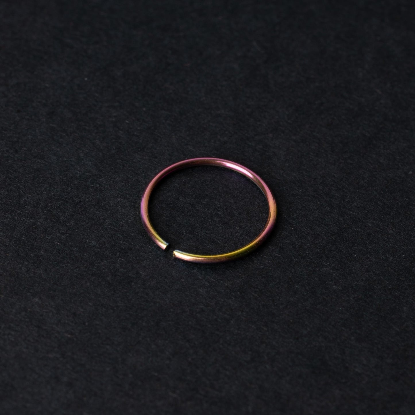 A single thin rainbow seamless hoop with a polished finish, displayed on a dark background.