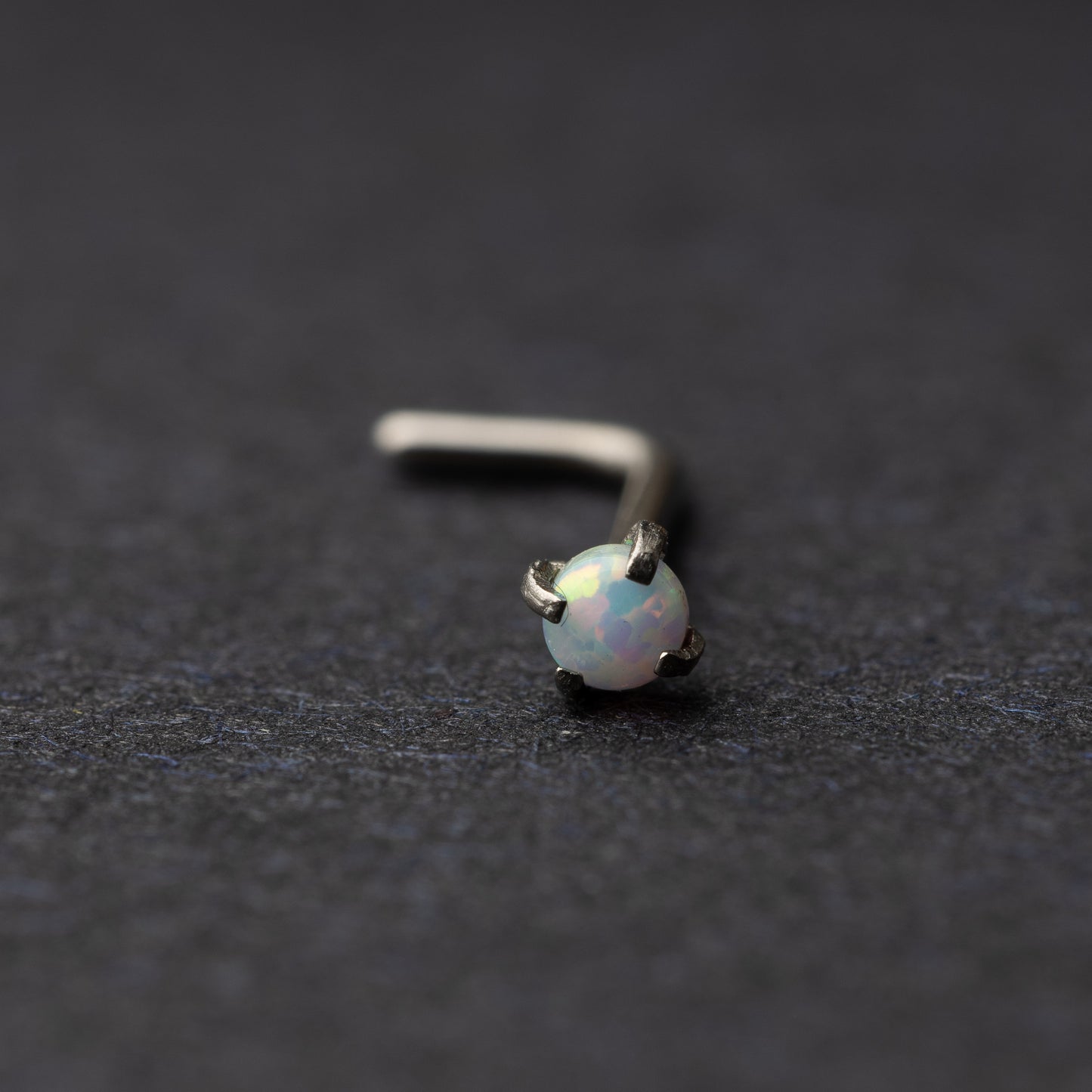 Opal L shaped nose stud on a dark background