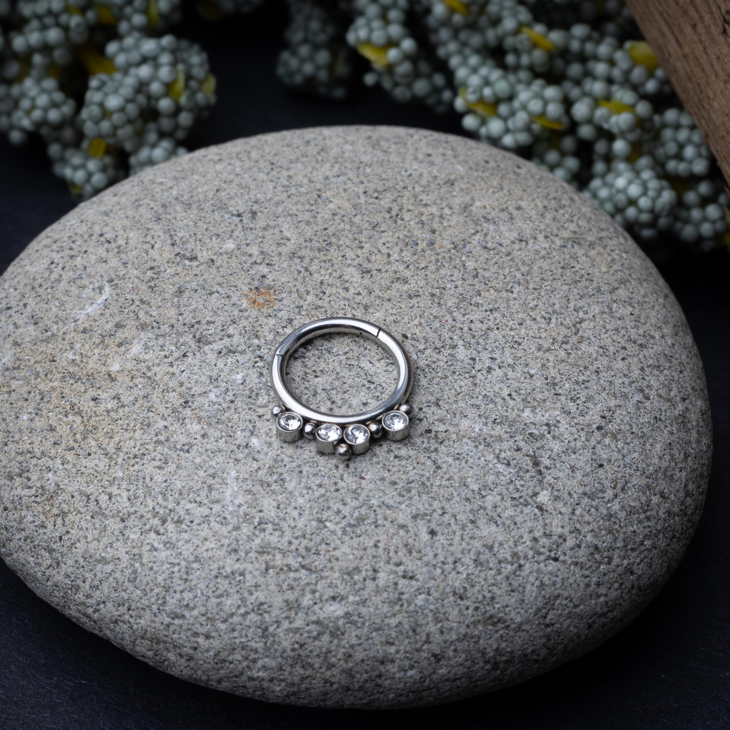 A stainless steel clicker with clear gemstones and bead accents, suitable for septum or daith piercings.
