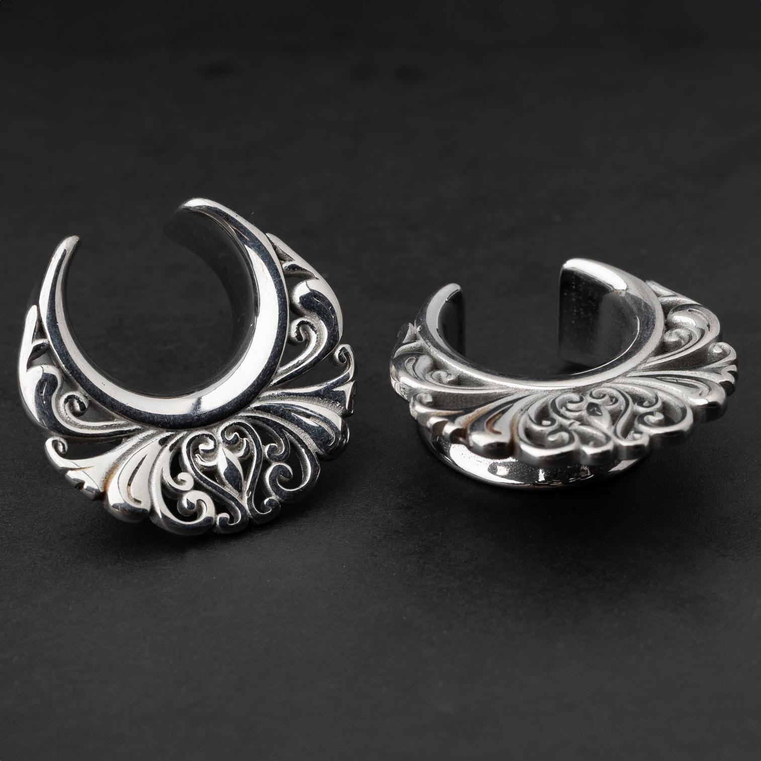 Pair of silver saddle tunnels with swirling decorative patterns for stretched ears.