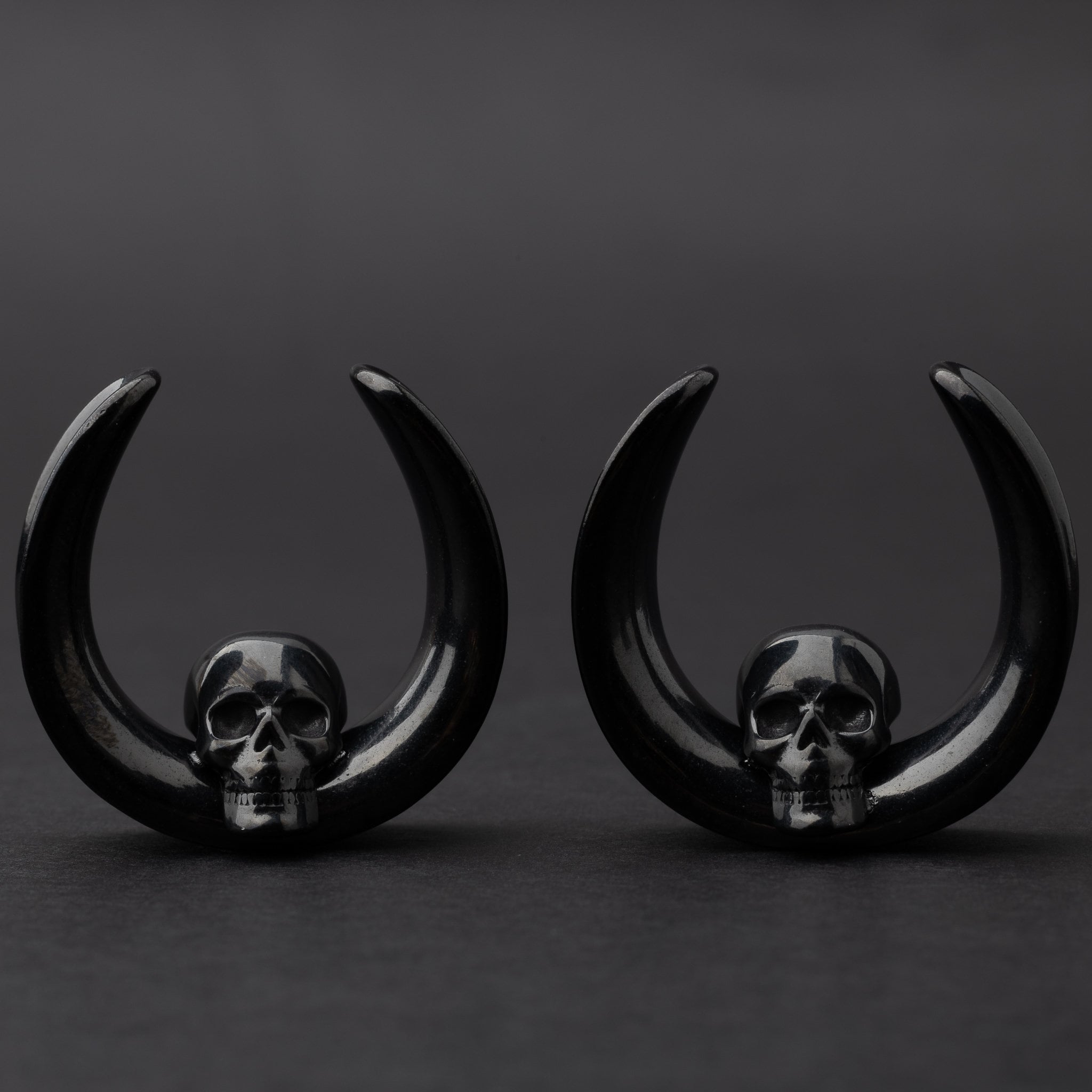 Pair of Skull design saddle tunnels in black, displayed on a dark background.