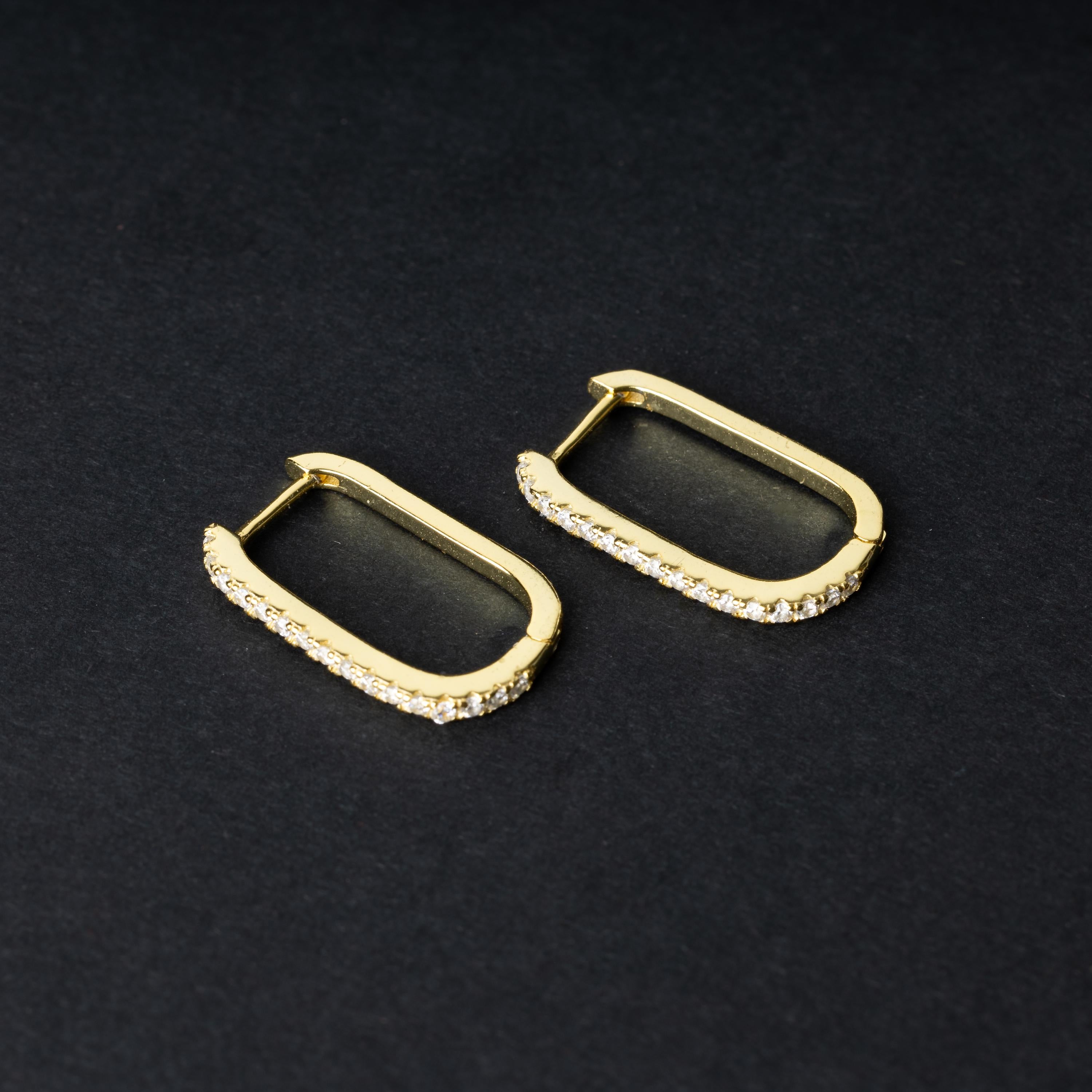 Pair of rectangular gold hoop earrings with crystal embellishments, displayed on a dark background.