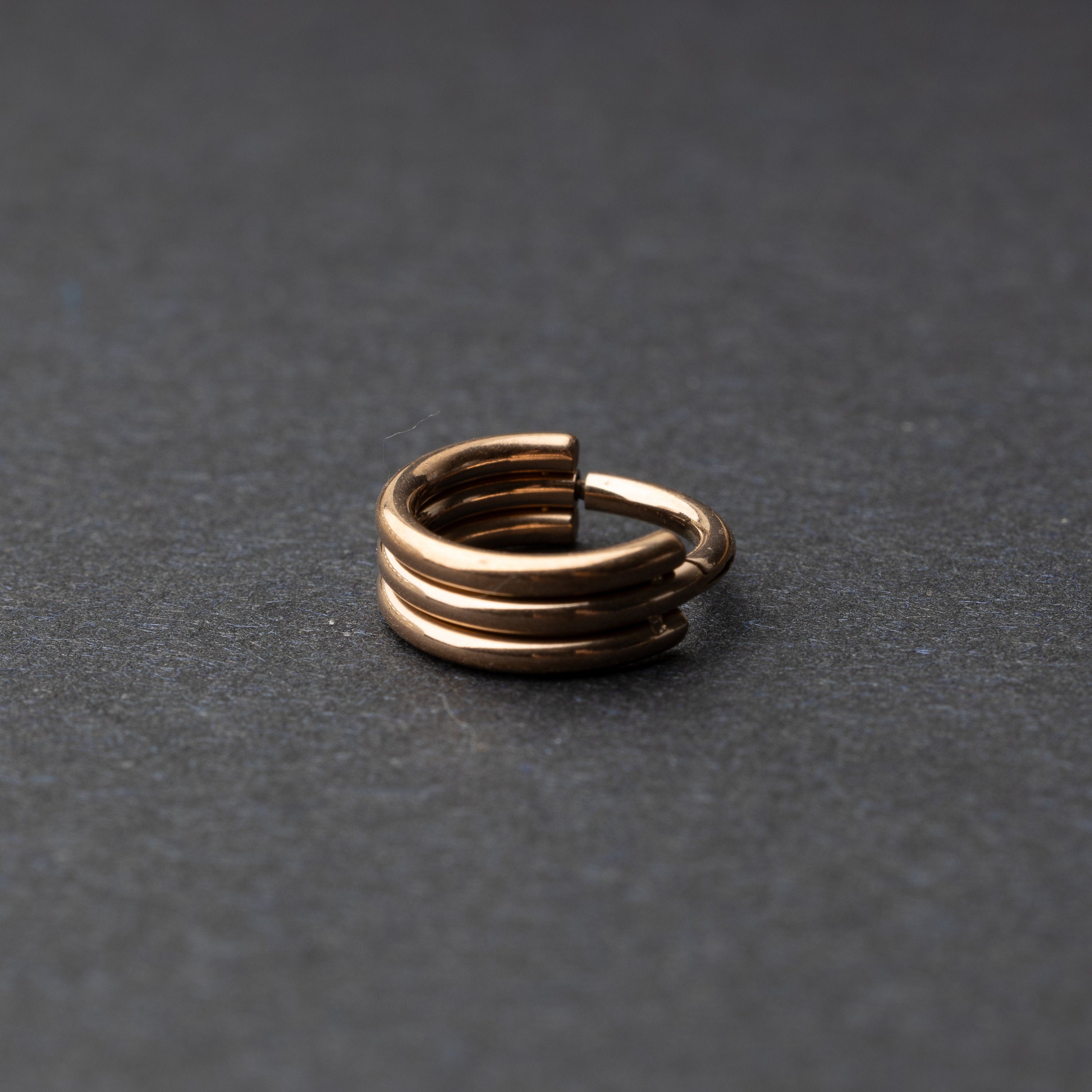 Triple-band seamless hoop rings in a Rose Gold finish displayed on a dark background, highlighting their sleek and modern design.