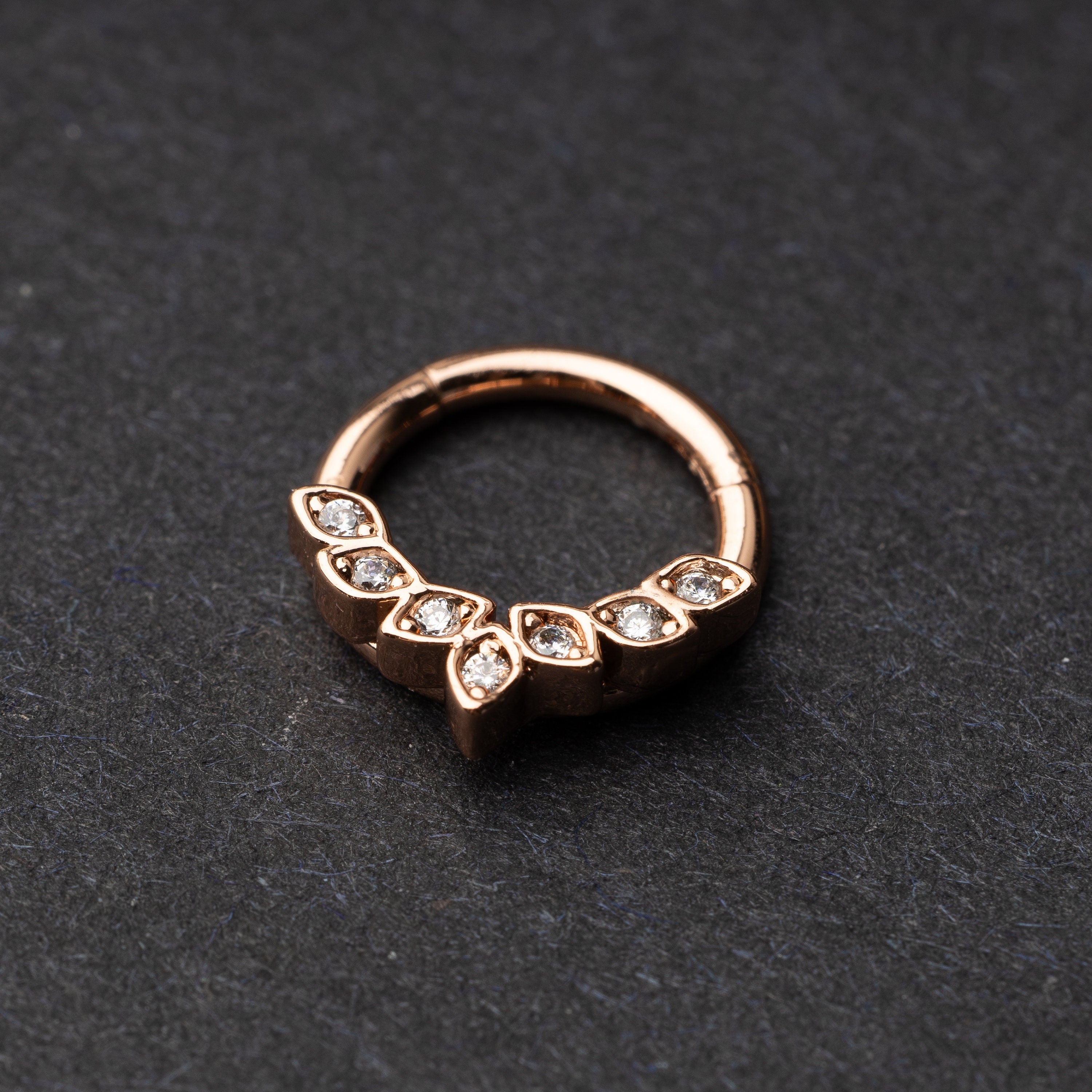 Marquise gemstone stainless steel clicker in rose gold displayed on a dark textured background.