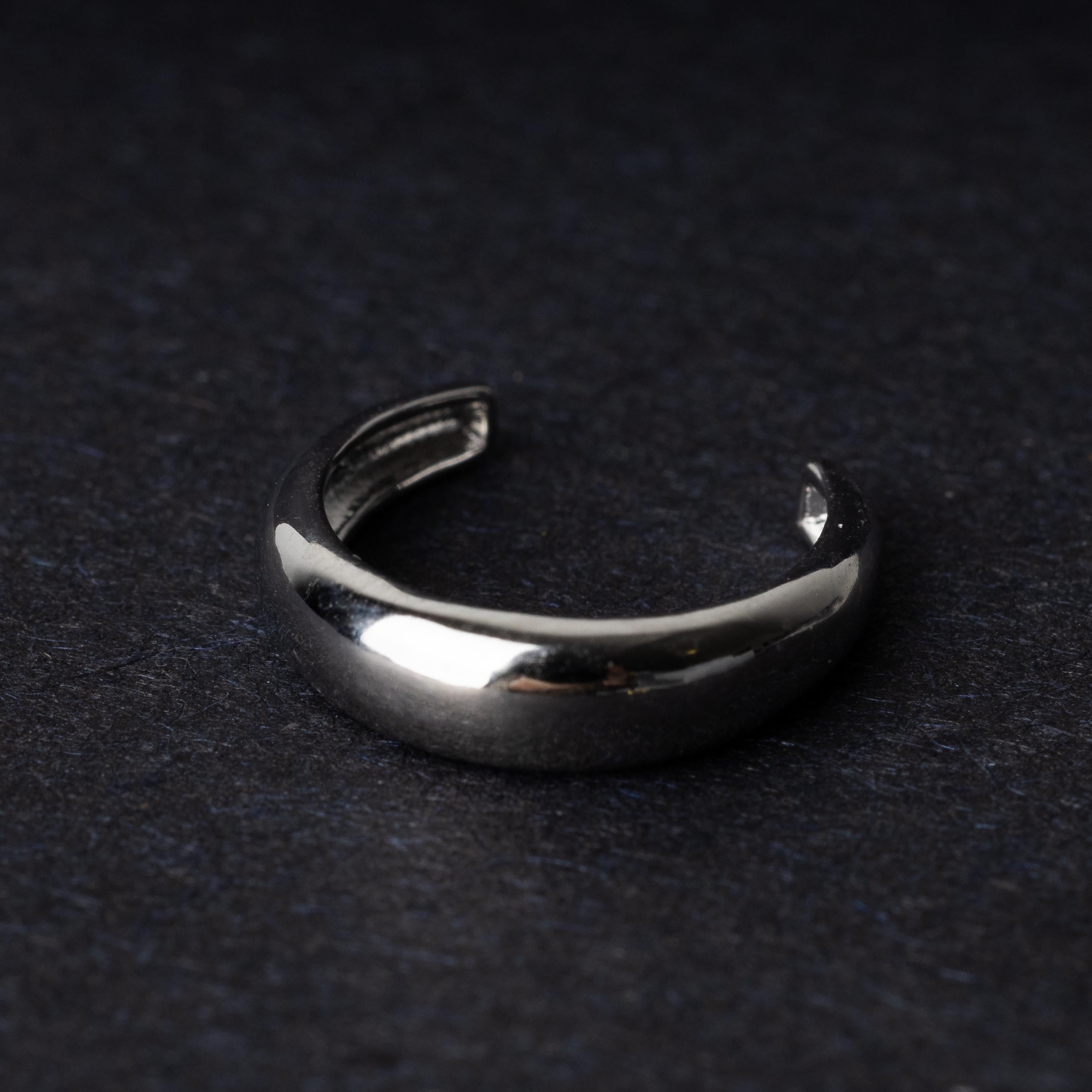 Bold ear cuff in silver with a smooth, domed design, displayed on a dark background.