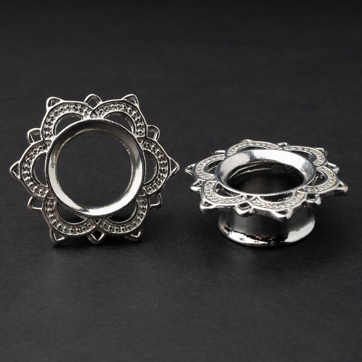 Silver flower-shaped tunnels with intricate detailing, displayed on a dark background.