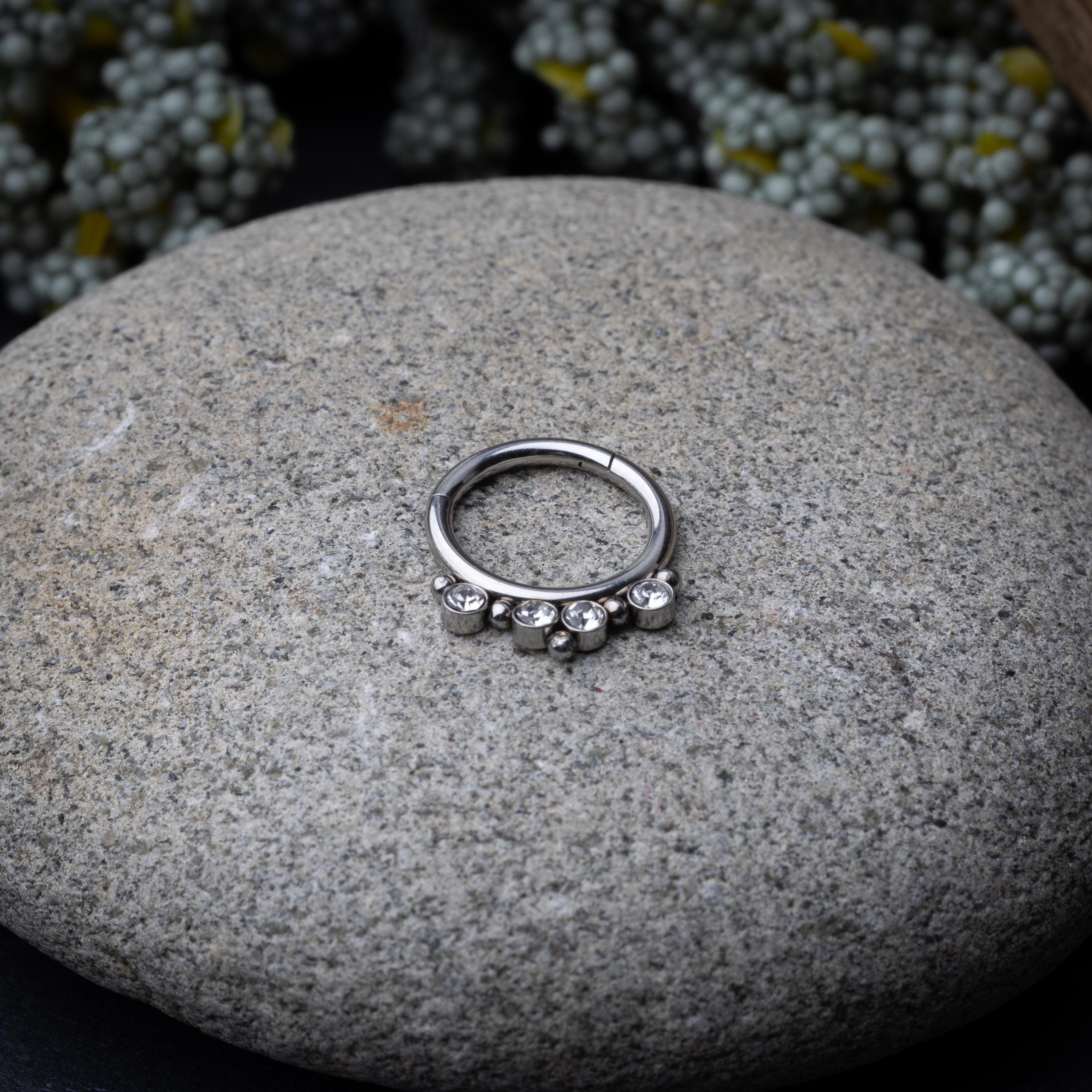 A stainless steel clicker with clear gemstones and bead accents, suitable for septum or daith piercings.