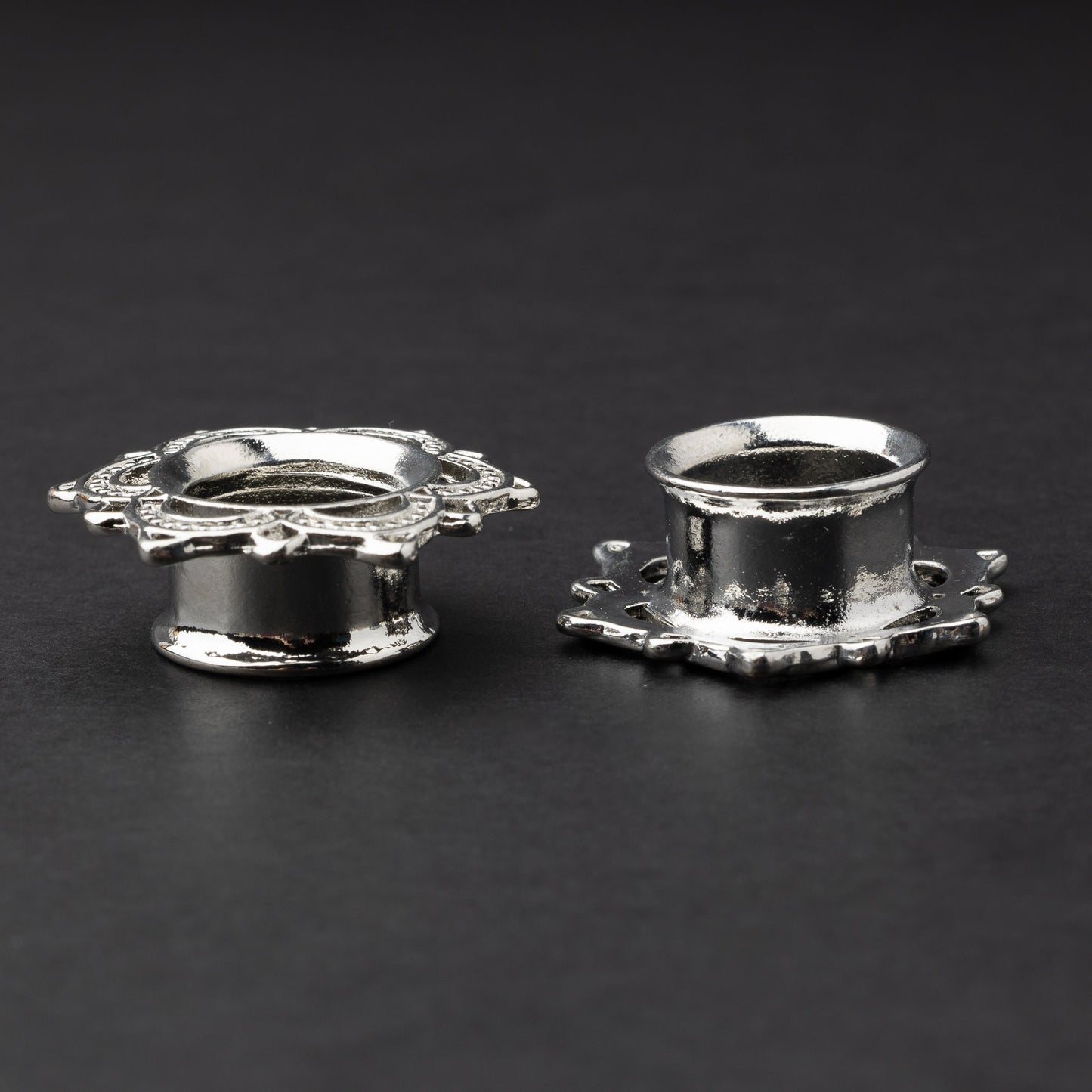 Silver flower-shaped tunnels with intricate detailing, displayed on a dark background.