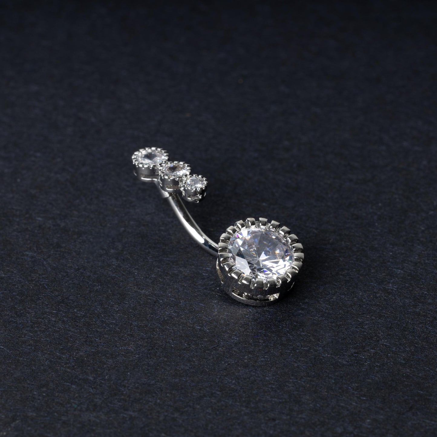 Double-jeweled belly rings in silver with large and small crystal accents, displayed on a dark background.