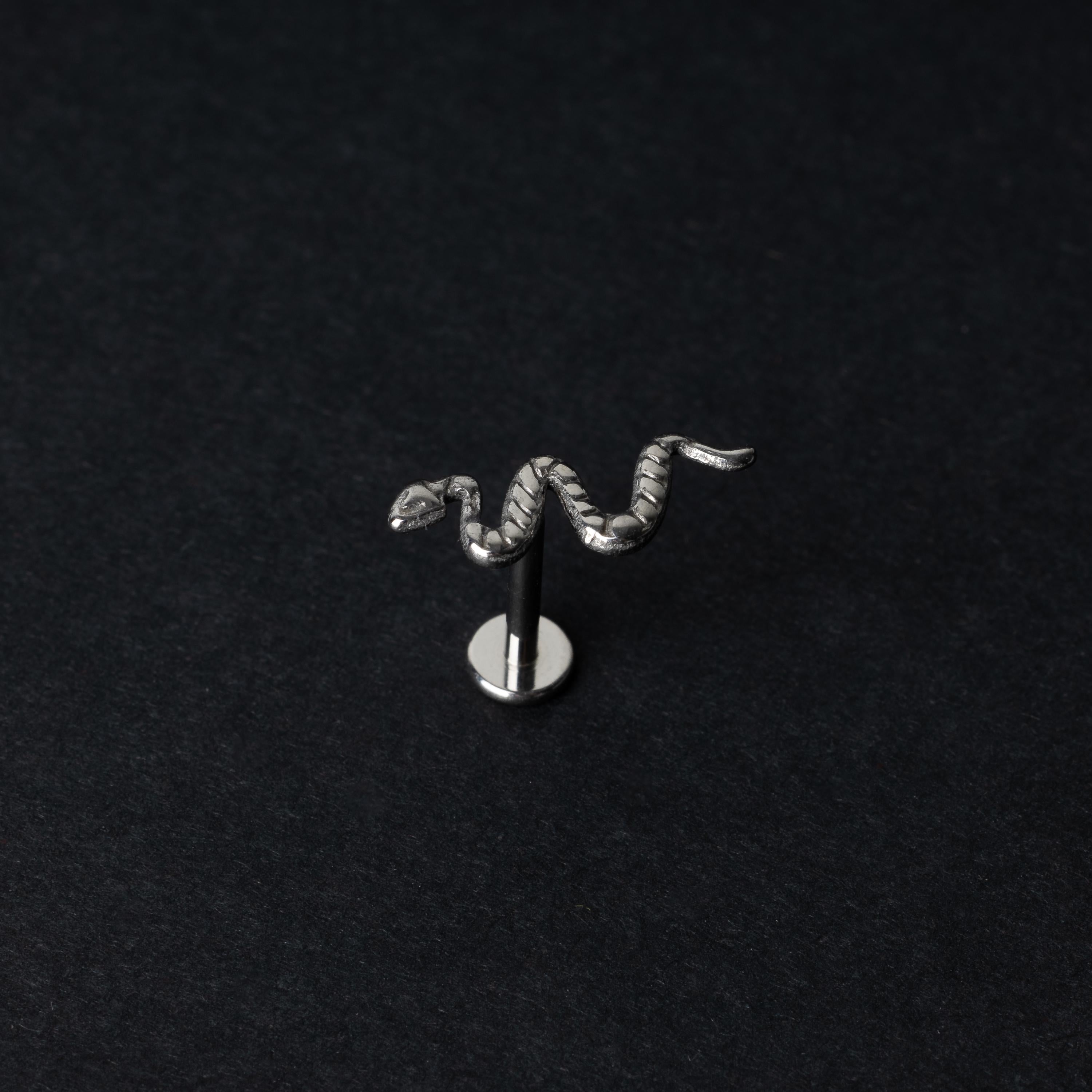 Silver-tone snake labret bars with intricate coiled snake designs displayed on a dark background.