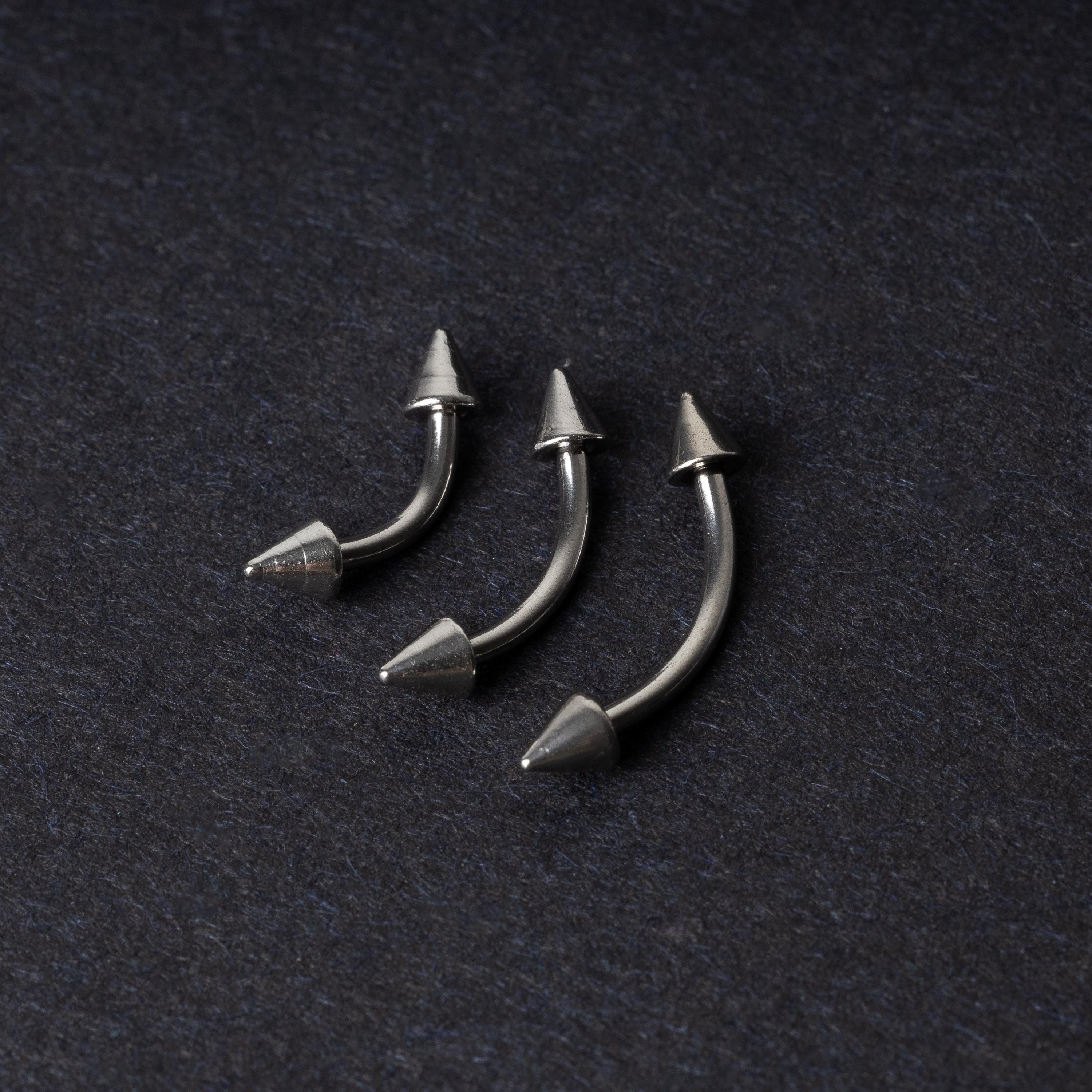 Three stainless steel curved barbells with cone-shaped ends, displayed on a dark background.