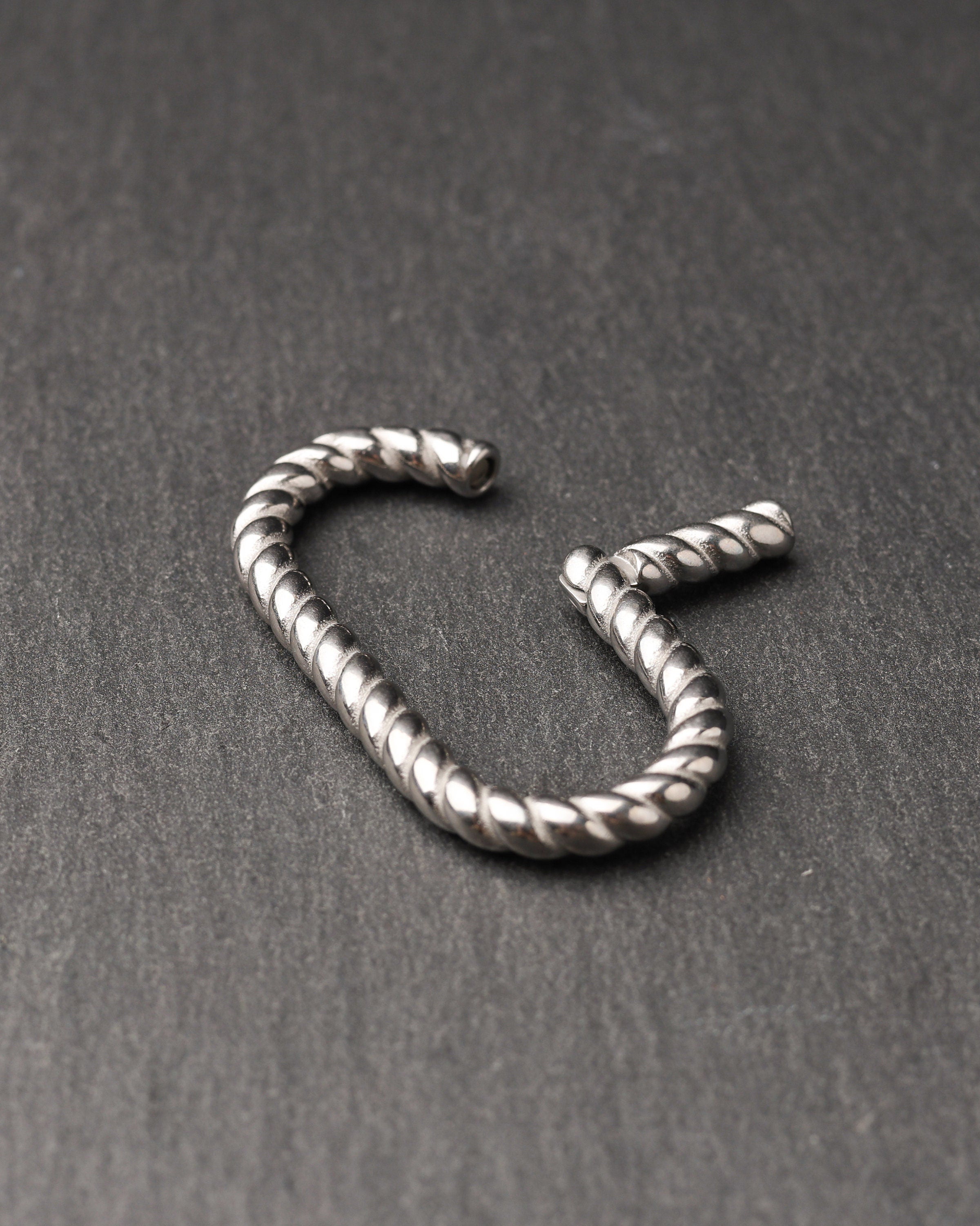 Twisted ear hangers in a silver finish displayed on a dark background, showcasing their rope-like design and bold style.