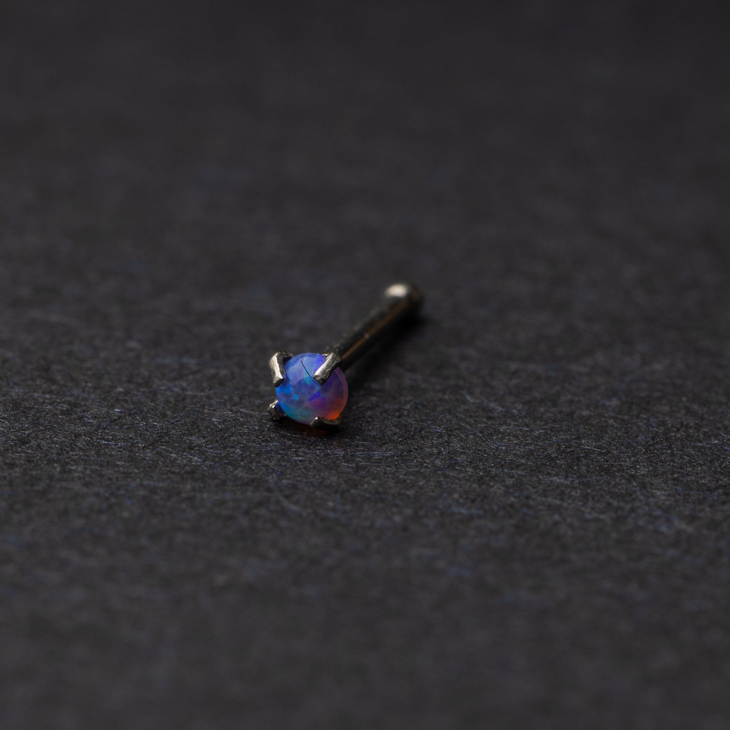 Dark blue nose stud displayed on a dark background