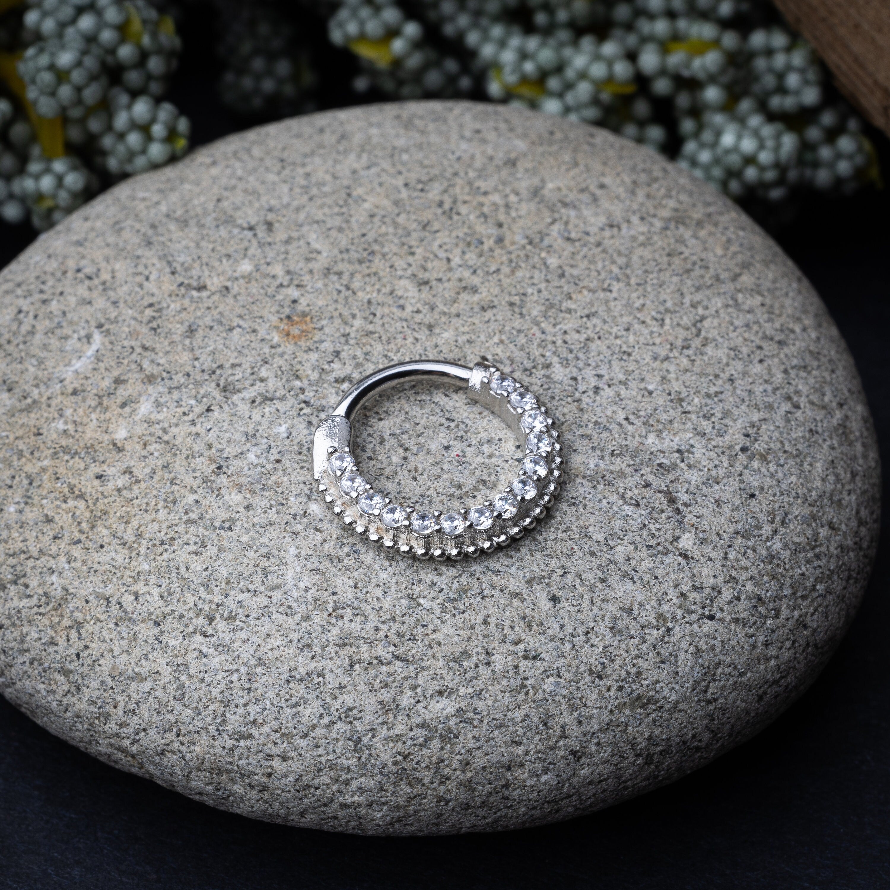 Stainless steel clicker with double rows of clear gemstones in silver displayed on a dark background