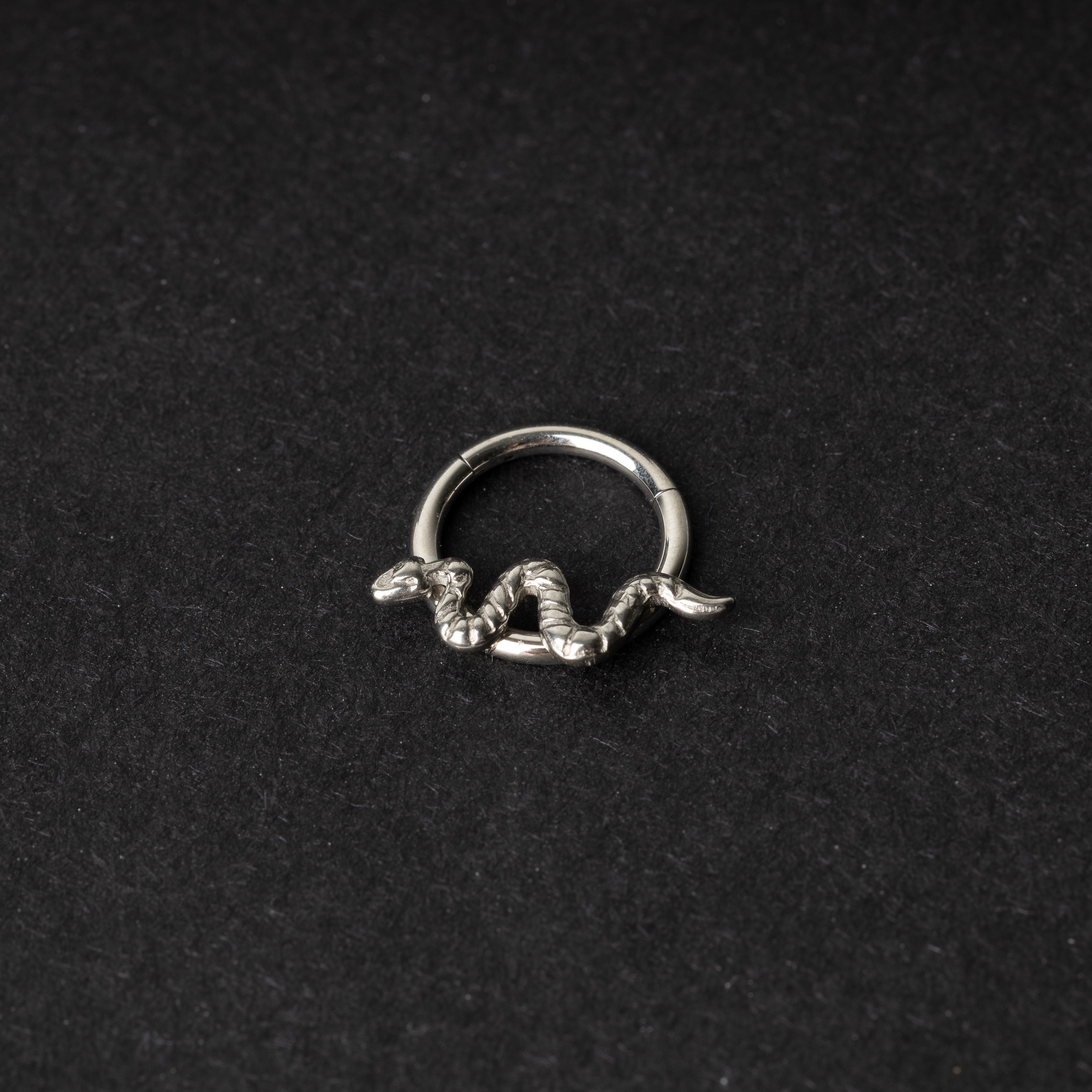 Silver snake clicker ring displayed on a dark background
