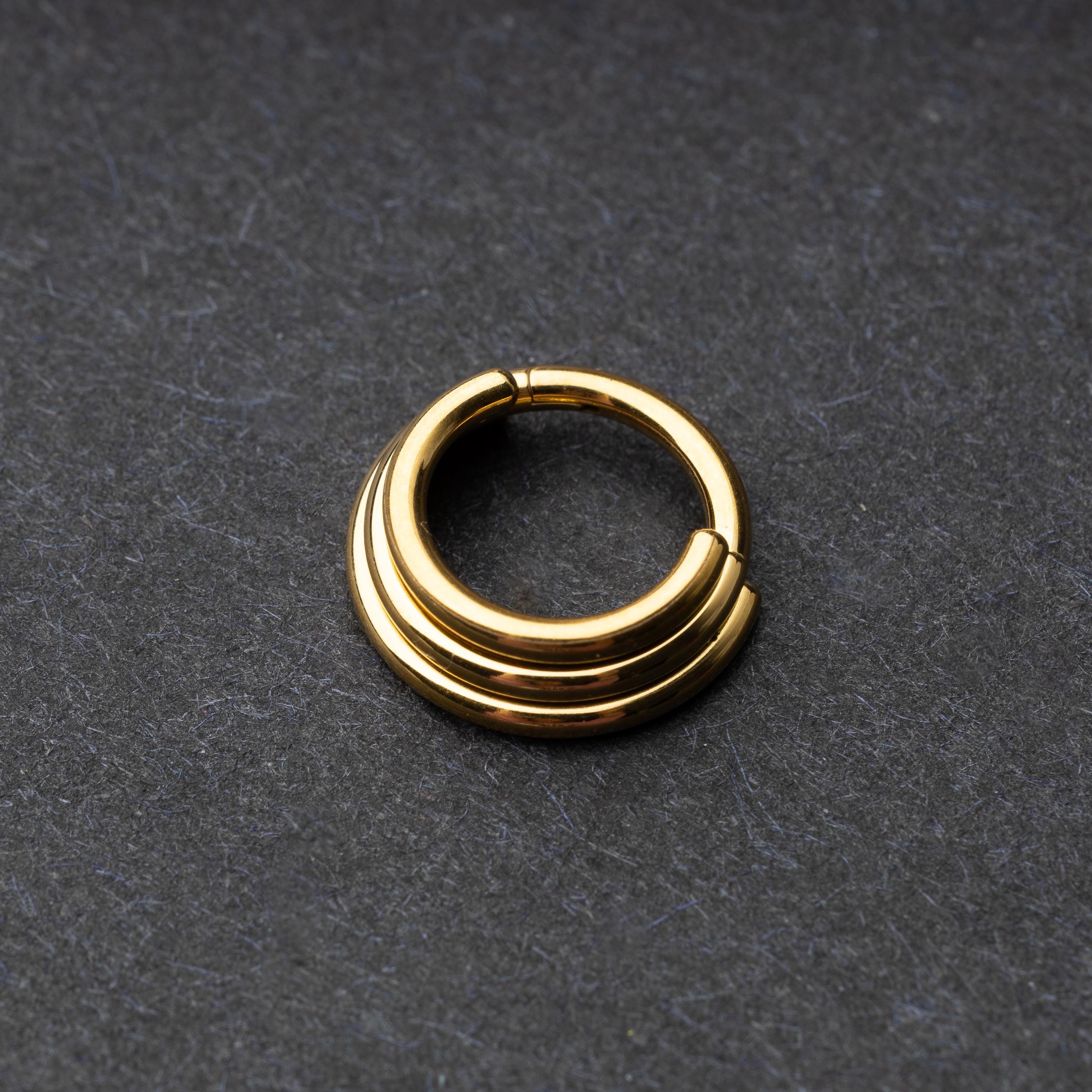 Stacked Septum Clicker in gold on a dark background.
