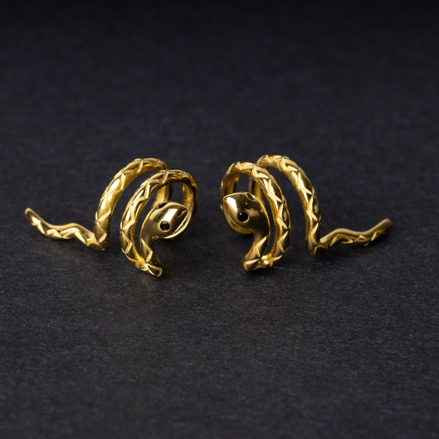 Gold-toned snake-shaped ear cuff made from 925 sterling silver, featuring a coiled design with intricate scales, displayed on a black background.