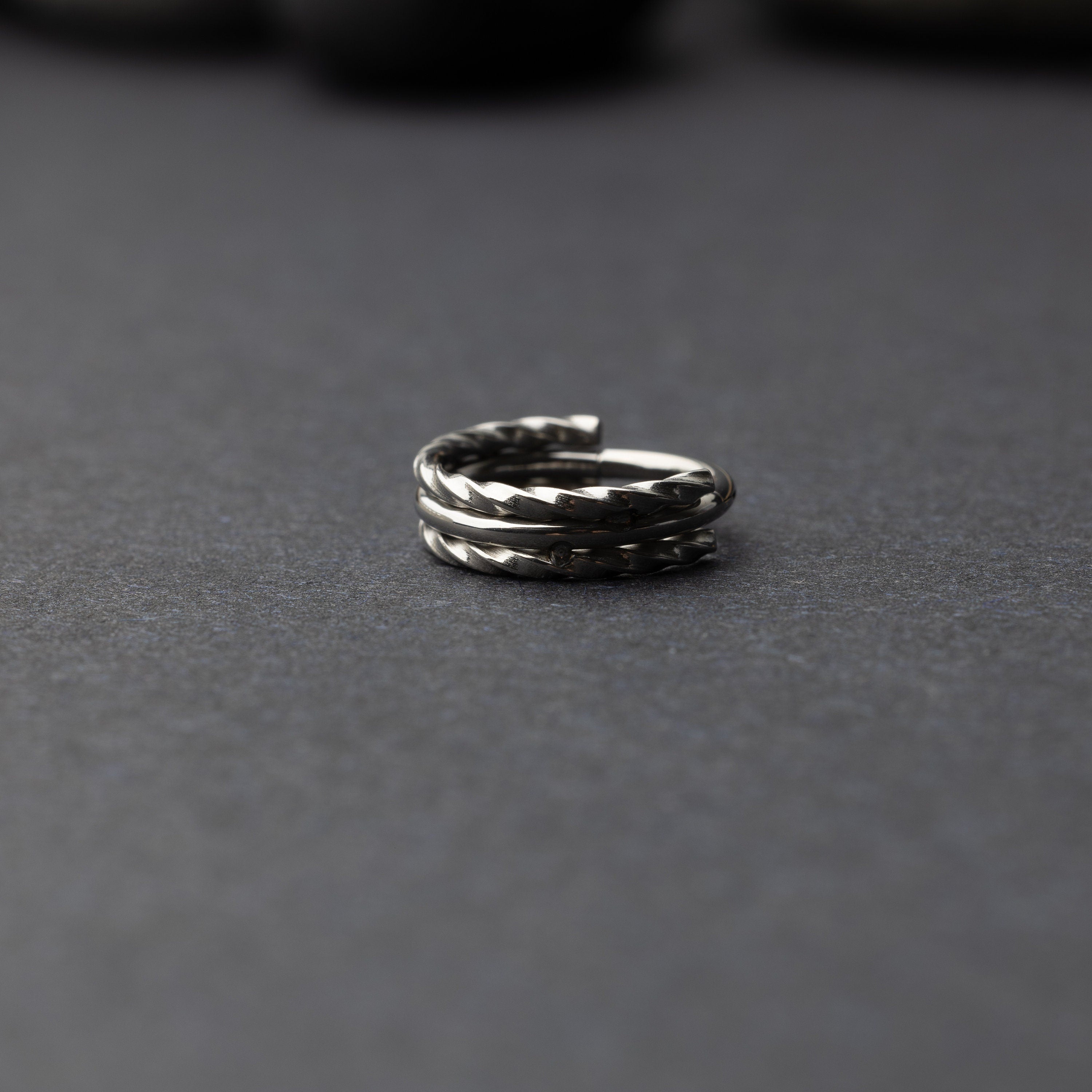 Textured stacked clicker in stainless steel finish with a triple-ring design, displayed on a dark background.