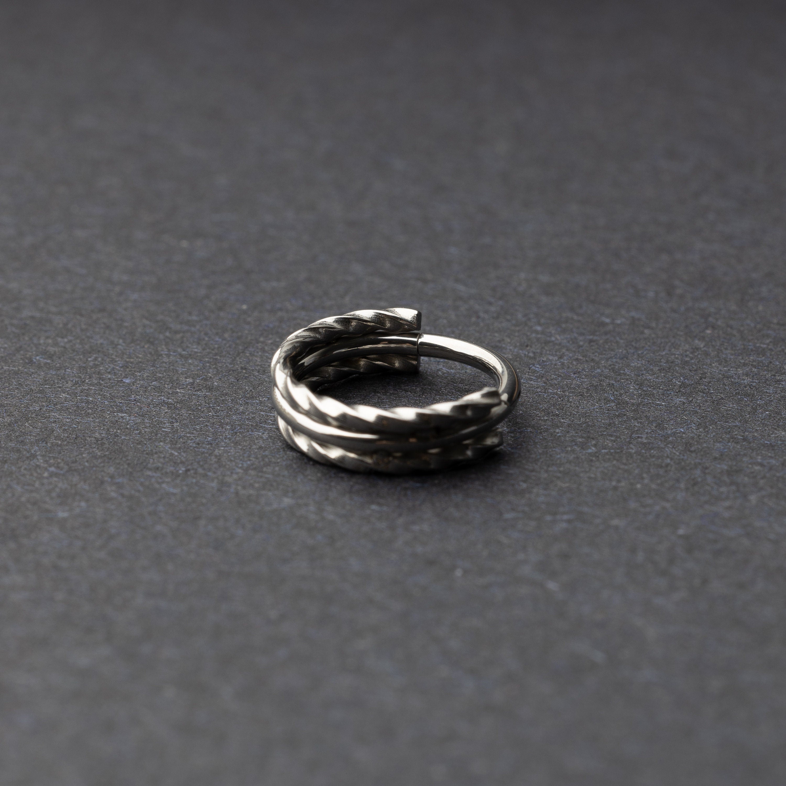 Textured stacked clicker in stainless steel finish with a triple-ring design, displayed on a dark background.