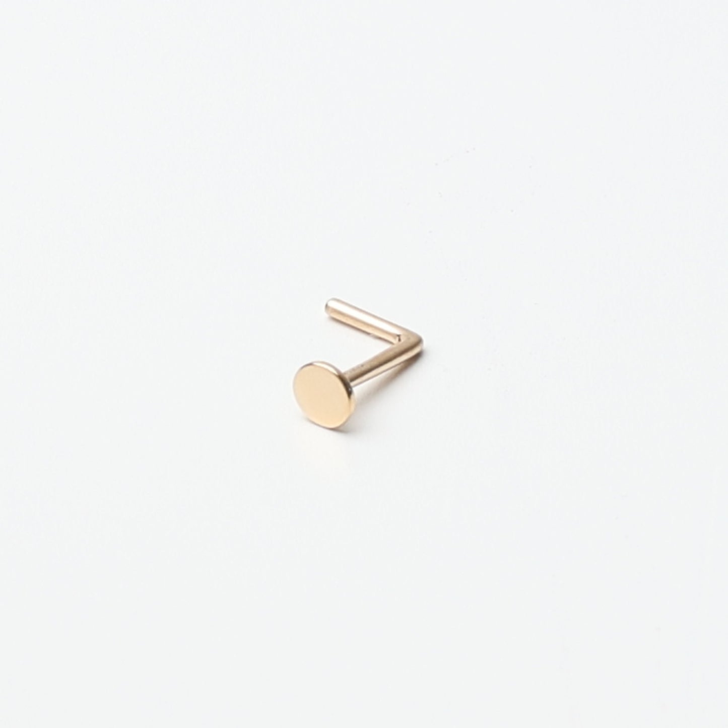 Solid gold nose stud with a flat disc design, displayed on a white background.