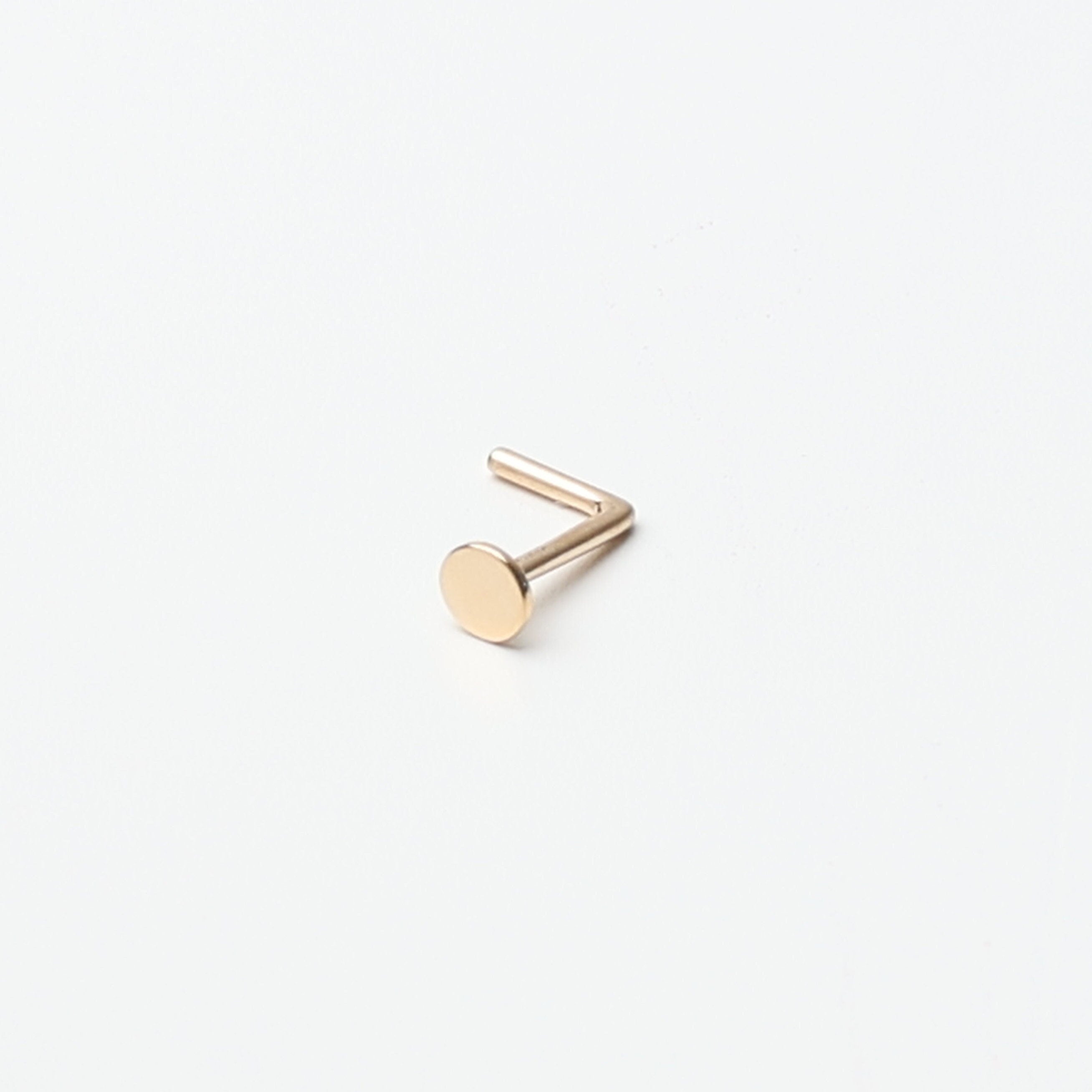 Solid gold nose stud with a flat disc design, displayed on a white background.