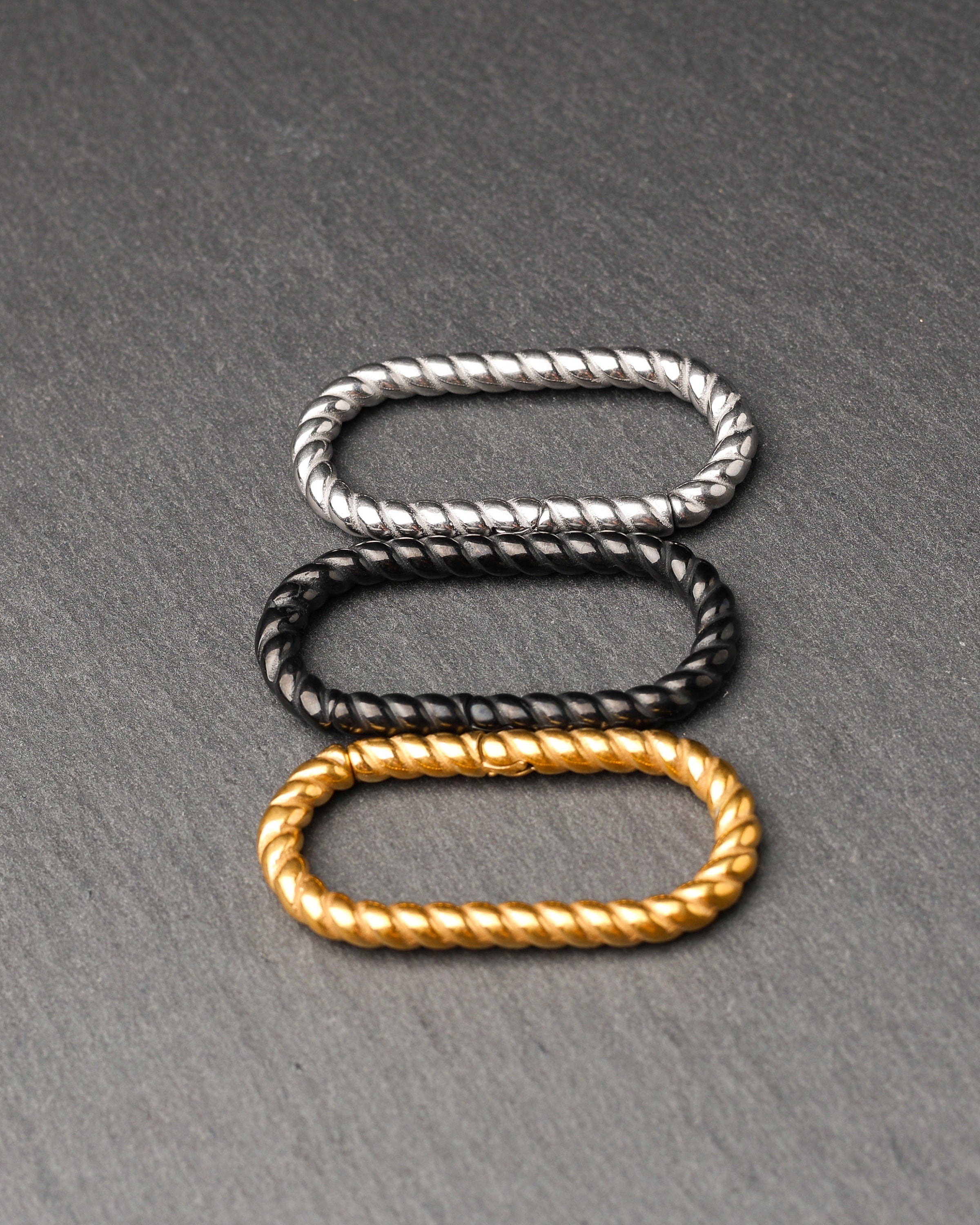 Twisted ear hangers in silver, black and gold finishes displayed on a dark background, showcasing their rope-like design and bold style.