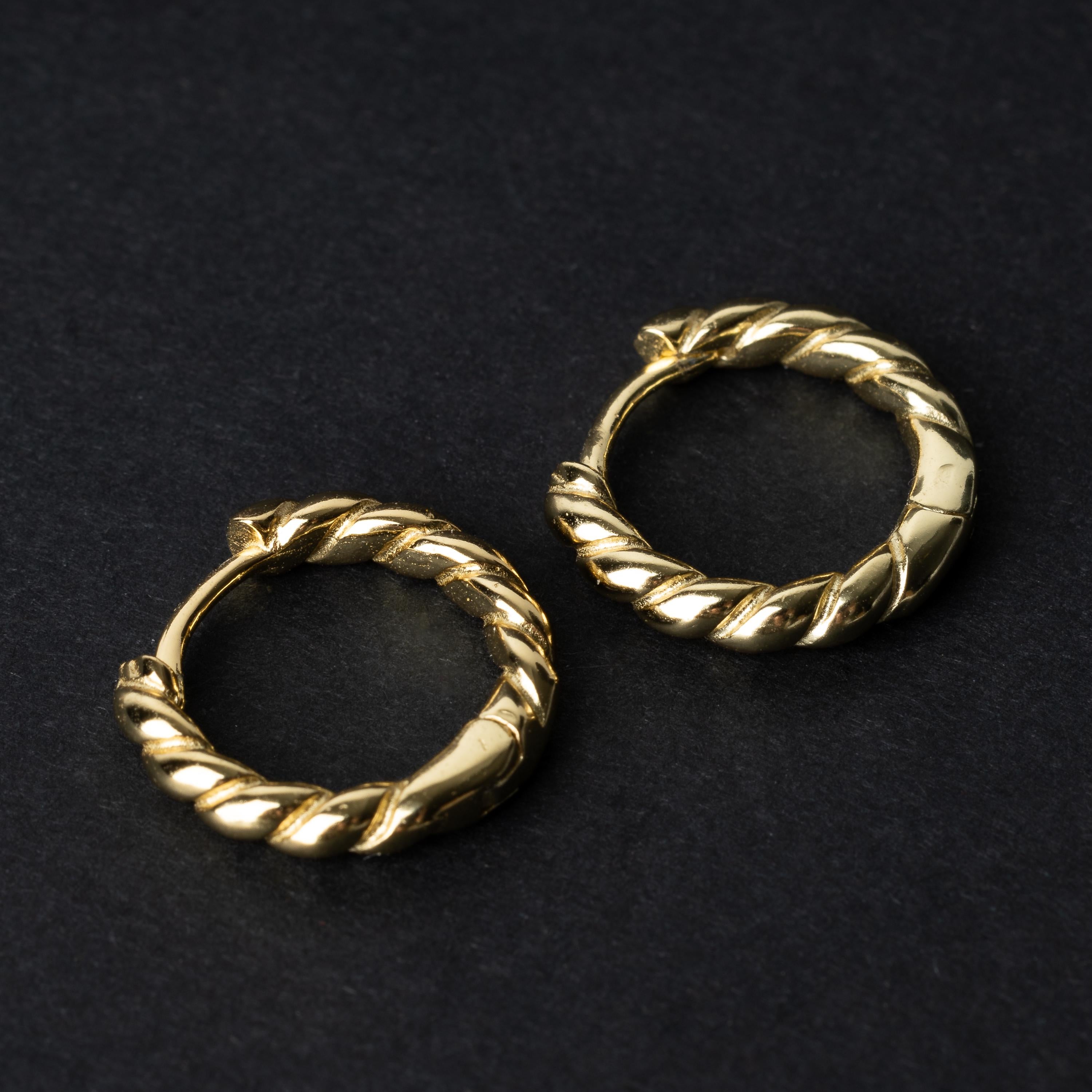 Pair of small gold braided hoop earrings, displayed on a dark background.
