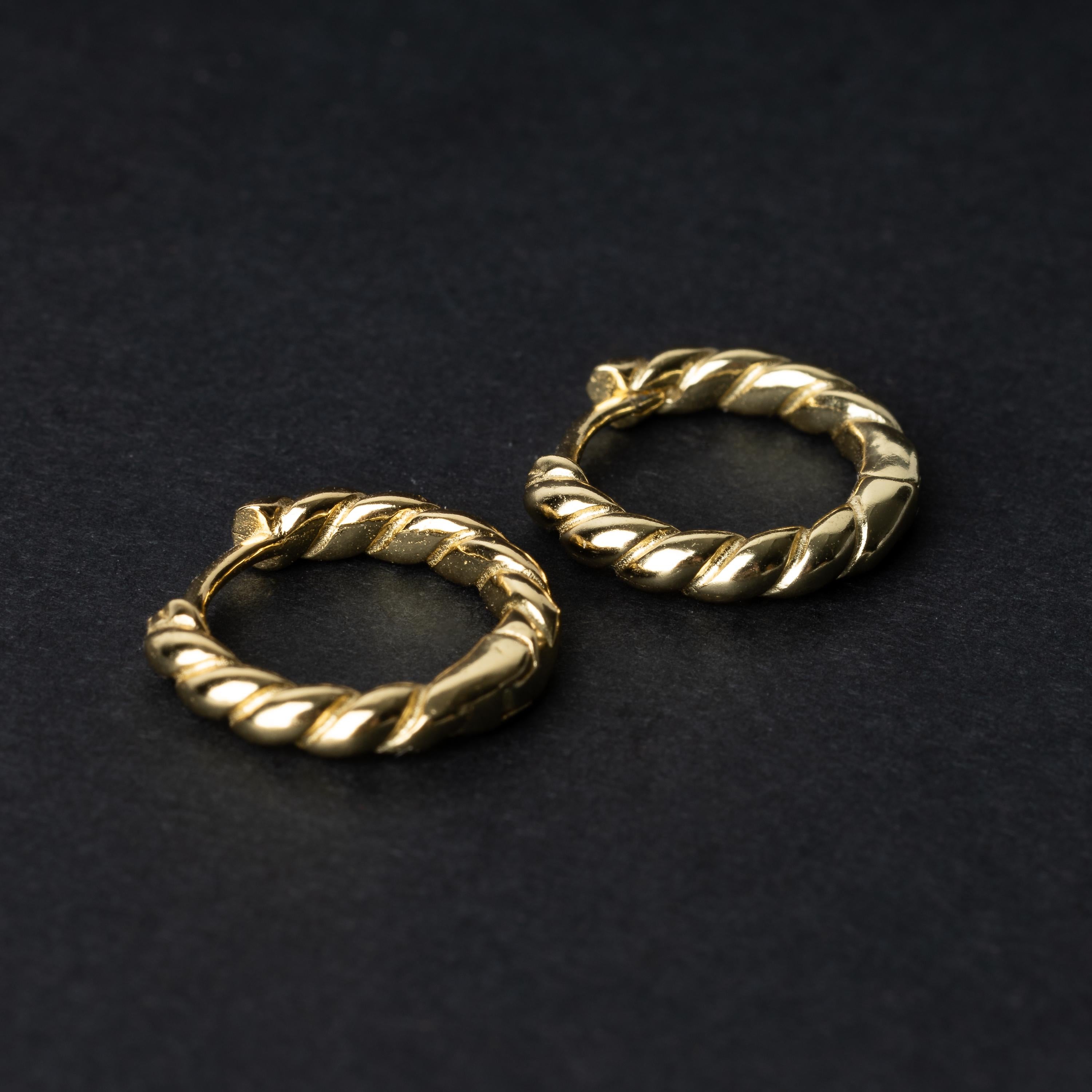 Pair of small gold braided hoop earrings, displayed on a dark background.