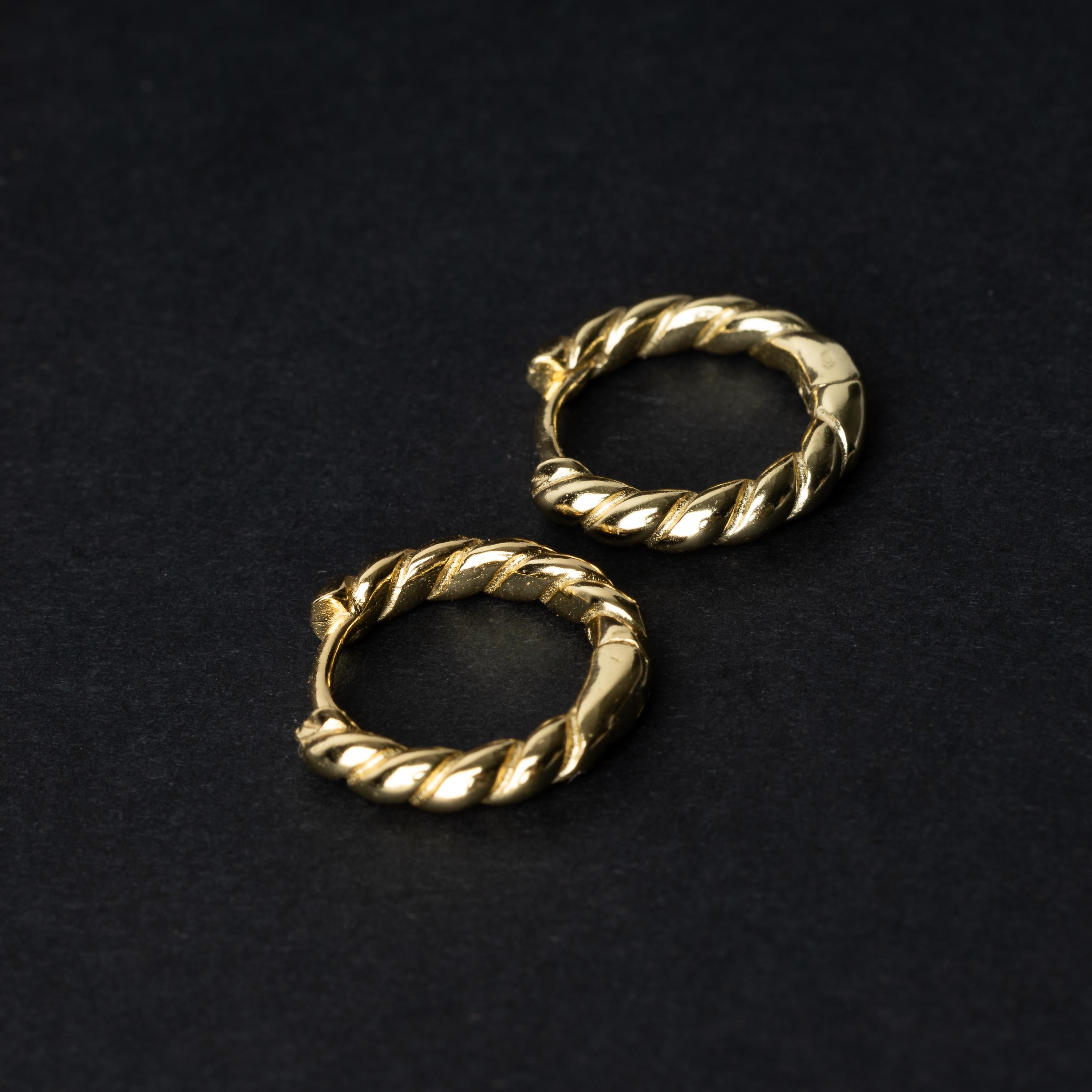 Pair of small gold braided hoop earrings, displayed on a dark background.