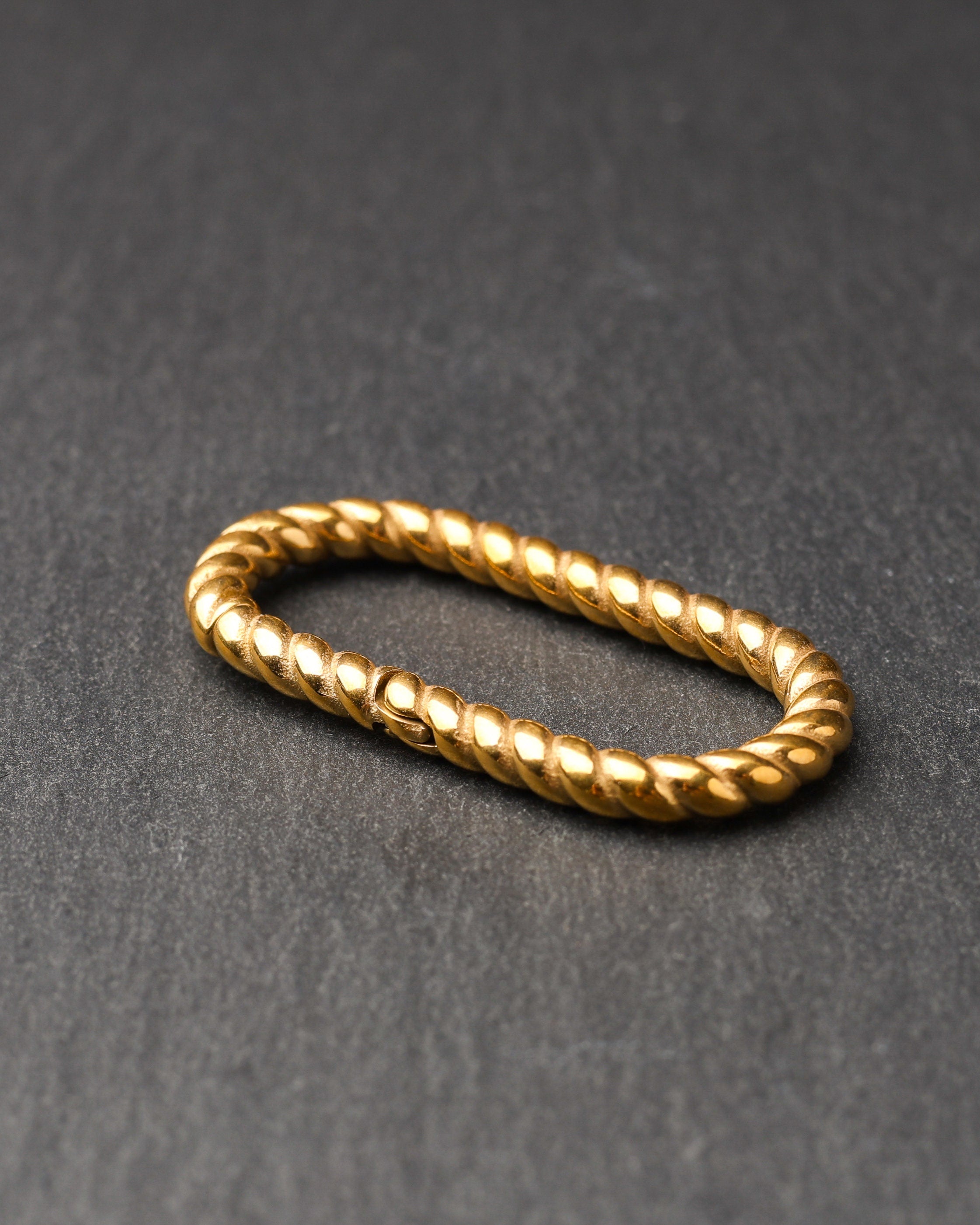 Twisted ear hangers in a gold finish displayed on a dark background, showcasing their rope-like design and bold style.