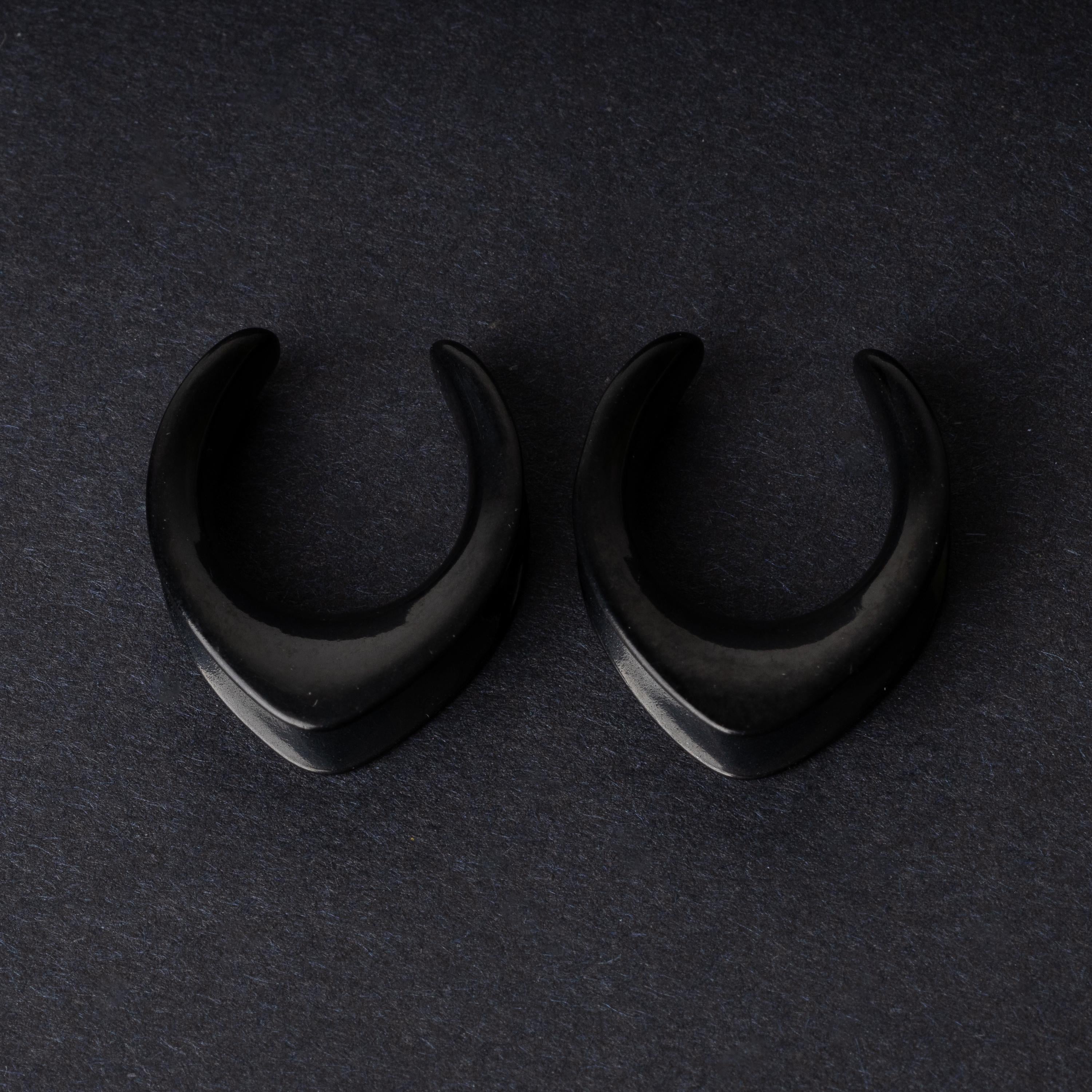 Double-flared metal tunnels for stretched ears in a gold finish, displayed on a dark background.