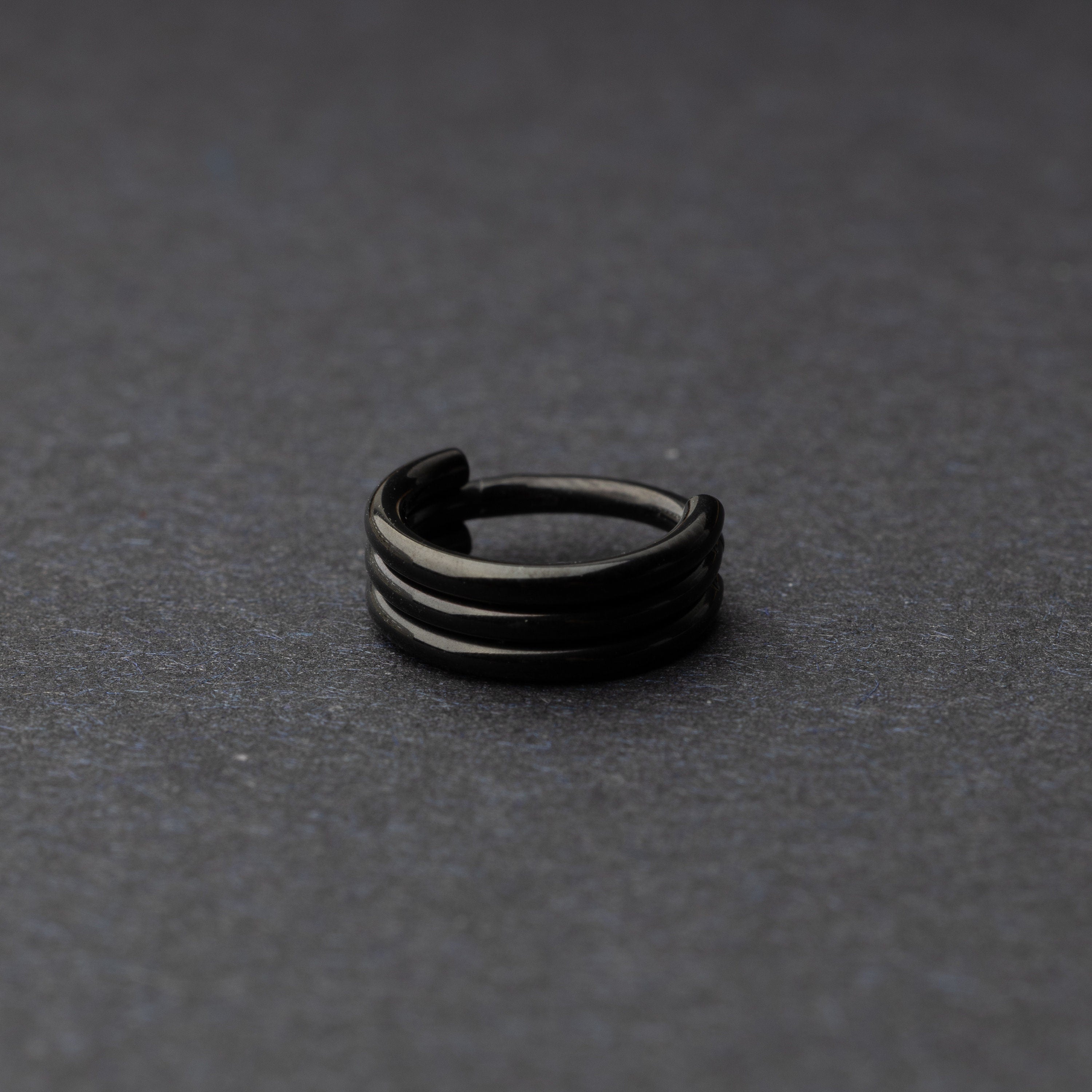 Triple-band seamless hoop rings in a back finish displayed on a dark background, highlighting their sleek and modern design.