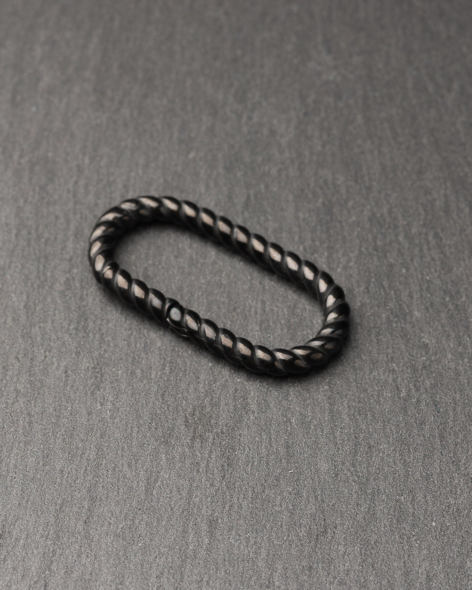 Twisted ear hangers in a black finish displayed on a dark background, showcasing their rope-like design and bold style.