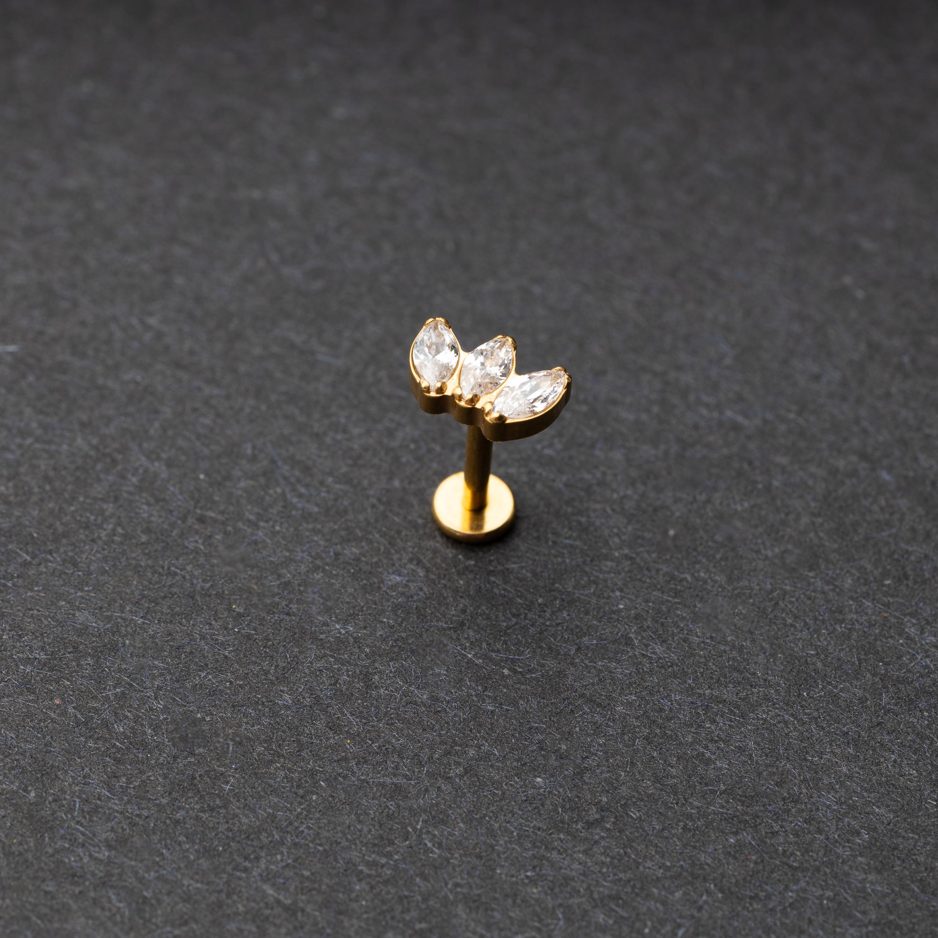flat back bar featuring a triple gem design with emerald clear gems on a gold base. displayed on a dark background.