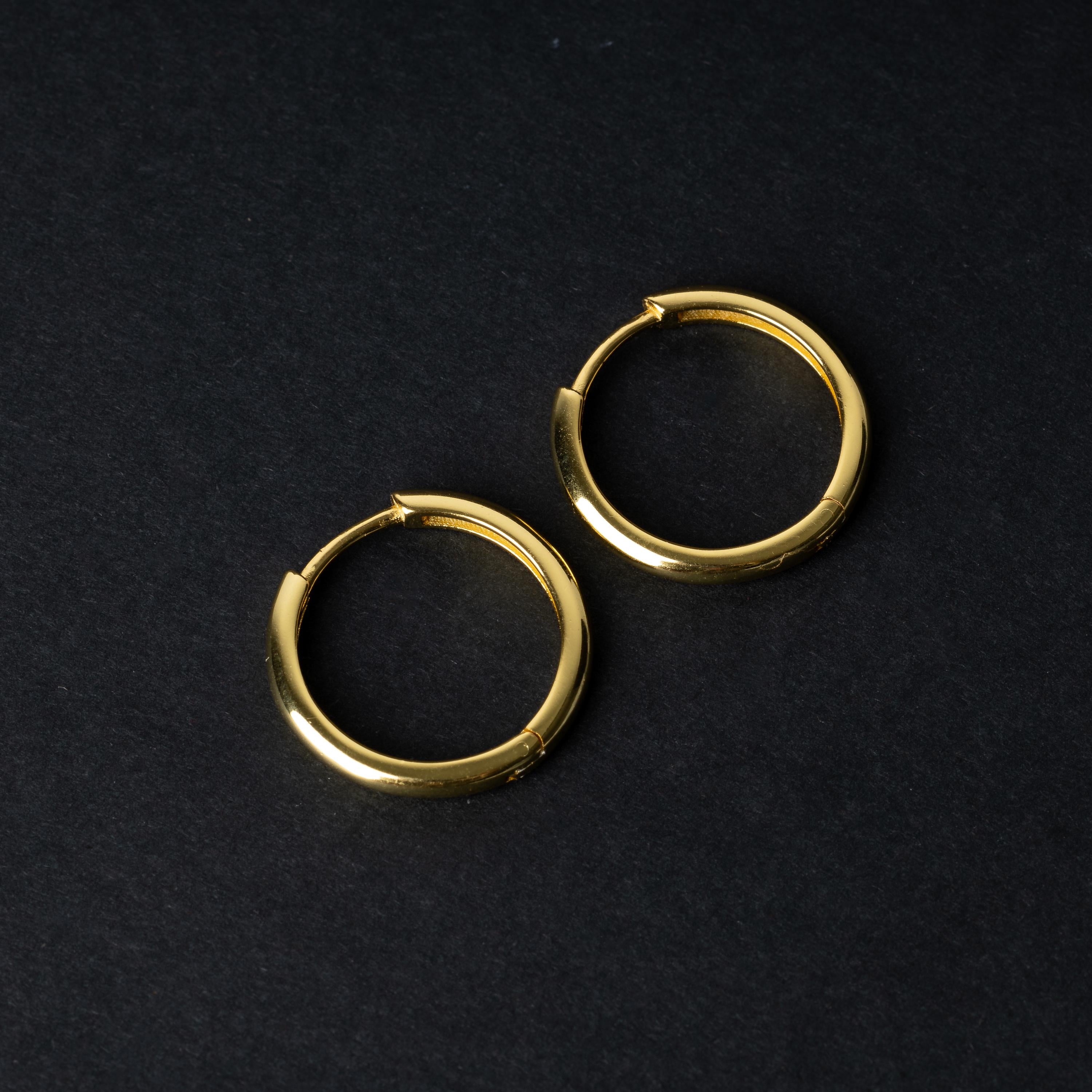 A pair of hoop earrings in gold displayed on a dark background