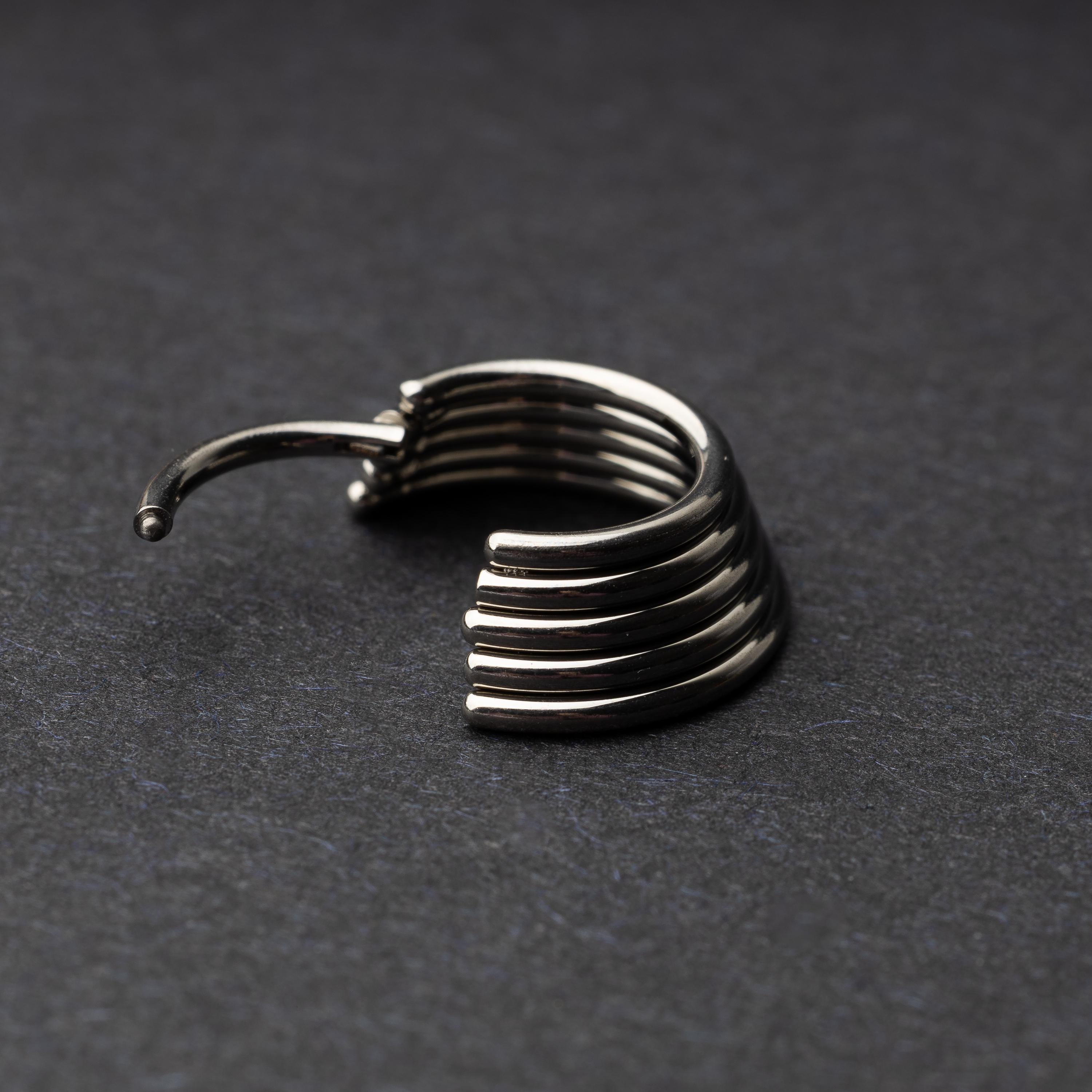 A silver-tone septum clicker with a stacked multi-ring design, displayed on a dark background, showcasing its bold and modern style.
