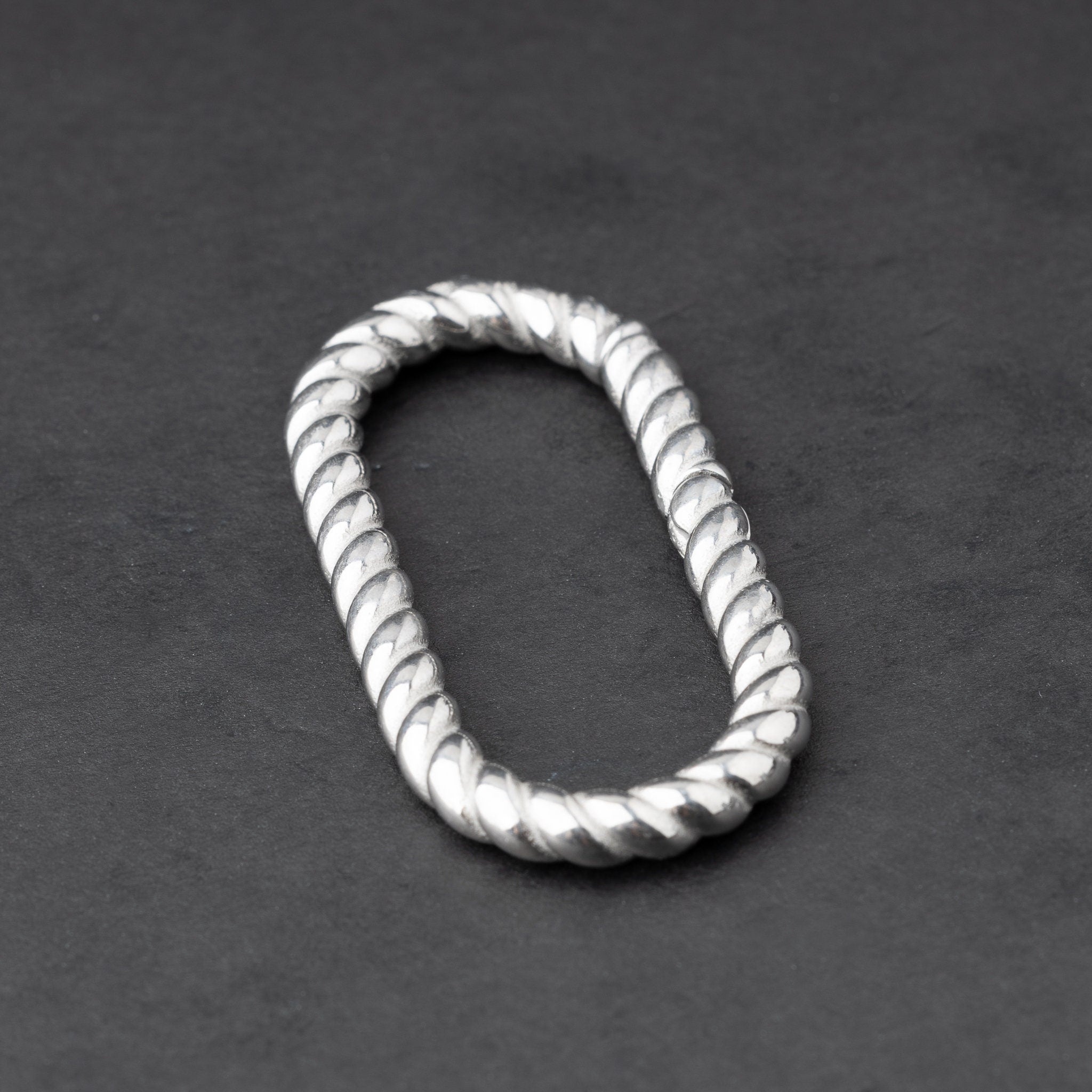 Twisted ear hangers in a silver finish displayed on a dark background, showcasing their rope-like design and bold style.