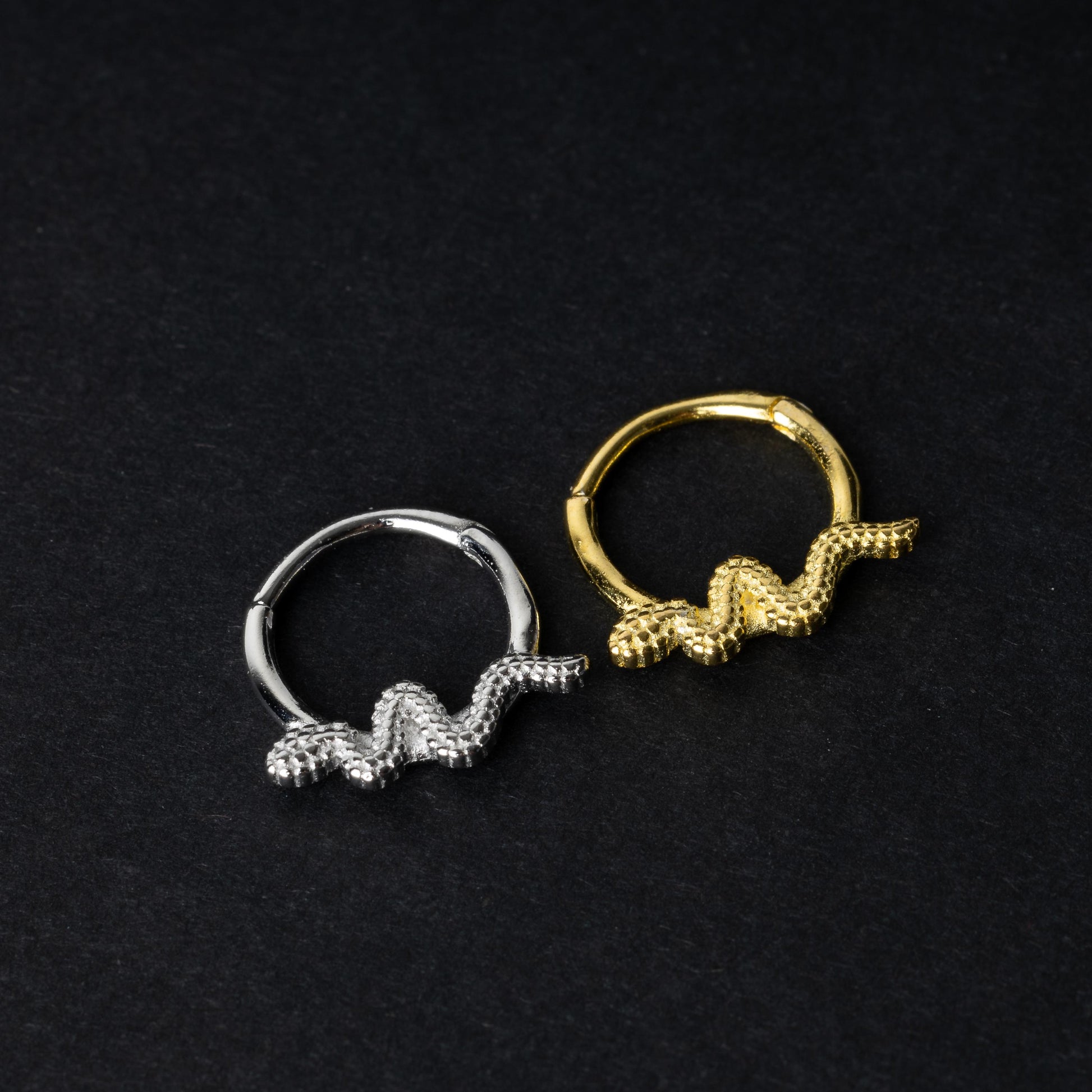 Silver and gold snake motif hinged rings crafted from 925 Sterling Silver on a dark background.
