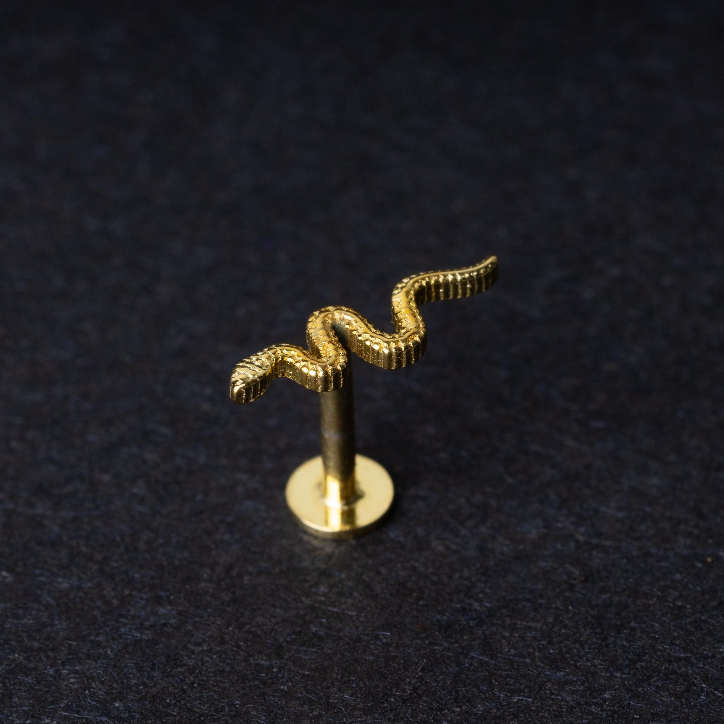 Gold-plated 925 sterling silver snake motif labret displayed on a dark background.