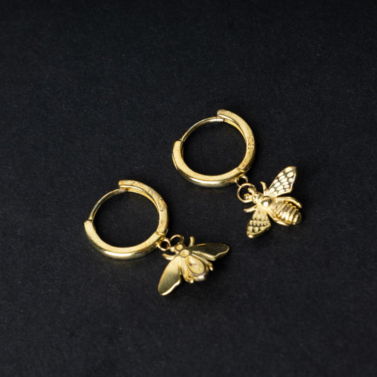 Gold hoop earrings with detailed bee and moth charms, displayed on a dark background.
