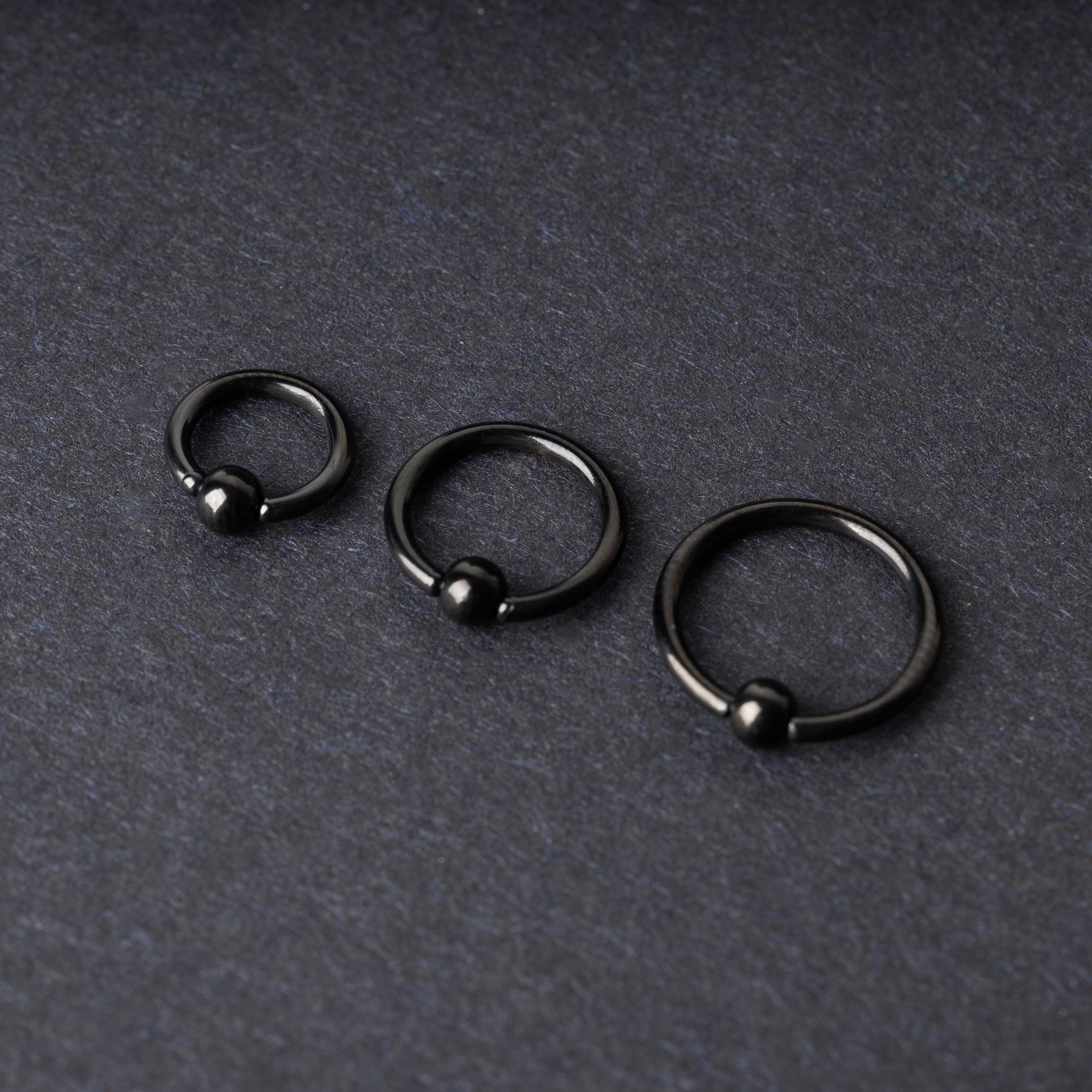 Three black ball closure rings (BCR) in varying sizes, displayed on a dark background with a polished finish and secure captive balls.