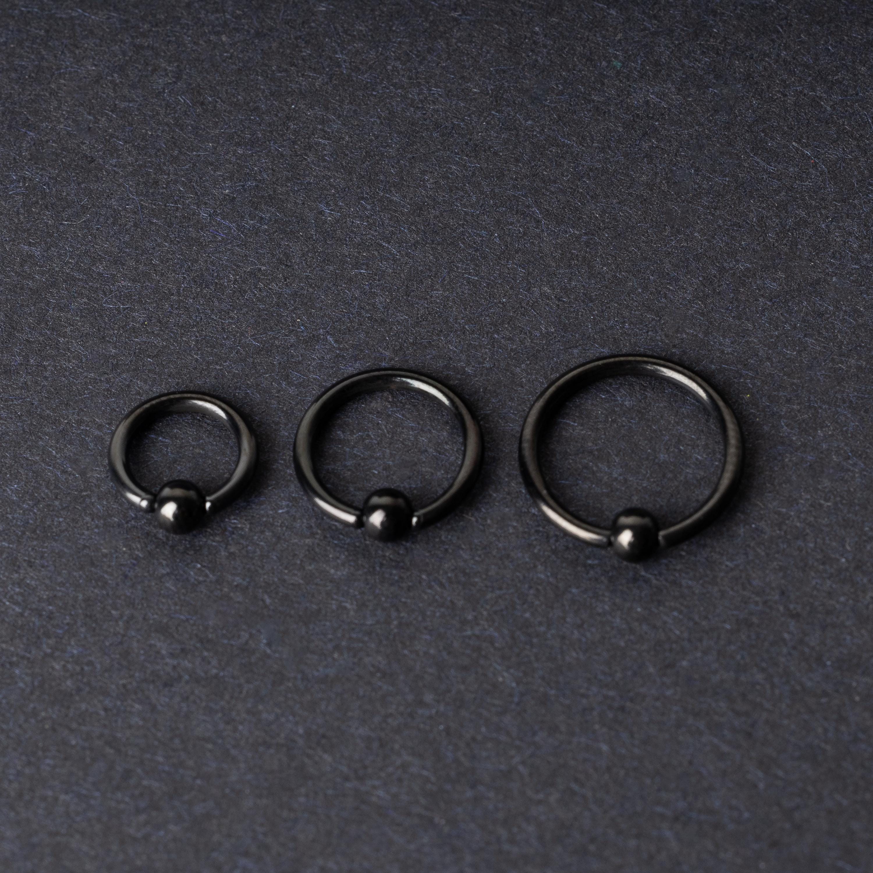 Three black ball closure rings (BCR) in varying sizes, displayed on a dark background with a polished finish and secure captive balls.