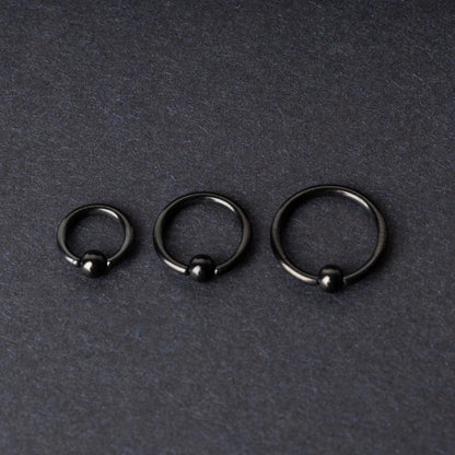 Three black ball closure rings (BCR) in varying sizes, displayed on a dark background with a polished finish and secure captive balls.