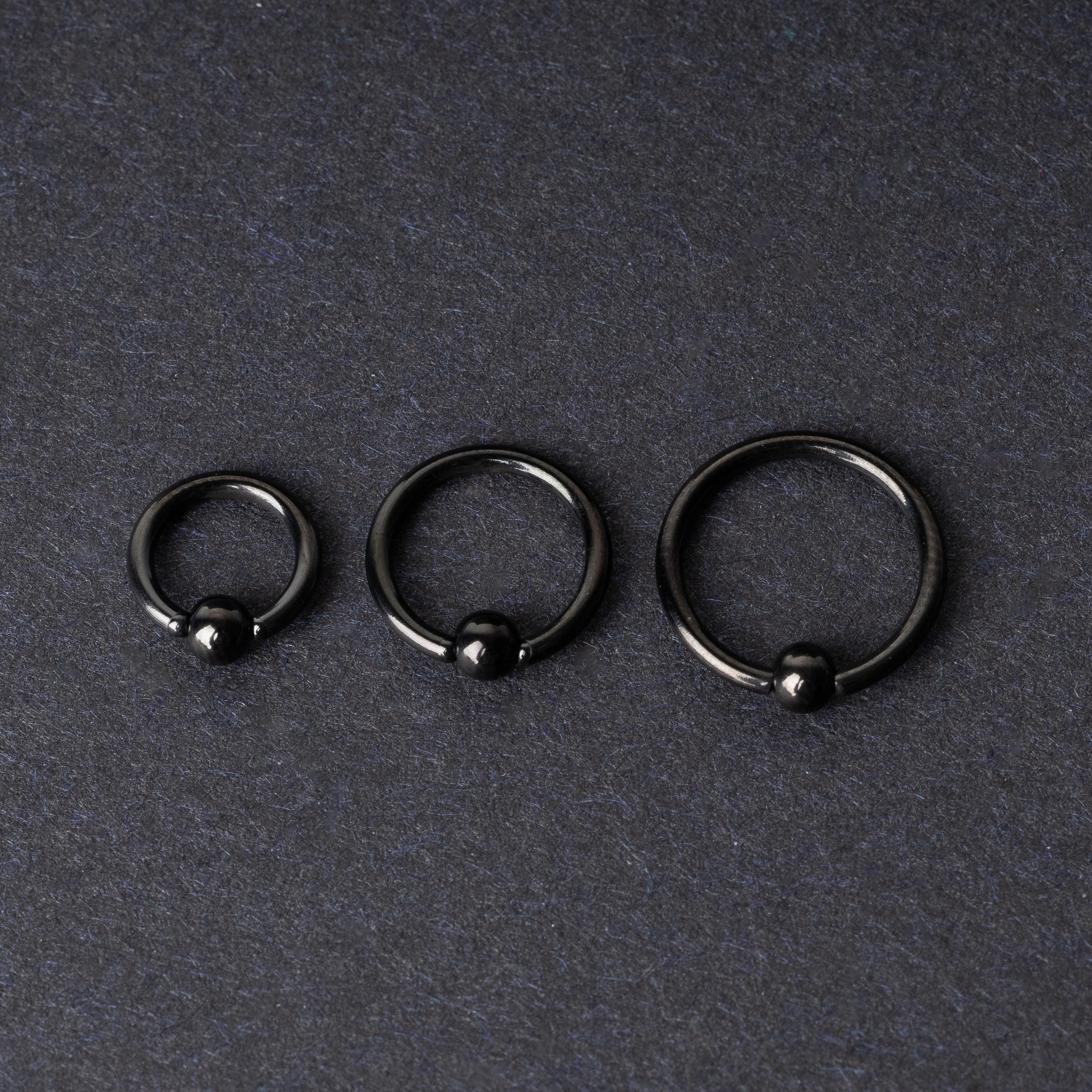 Three black ball closure rings (BCR) in varying sizes, displayed on a dark background with a polished finish and secure captive balls.