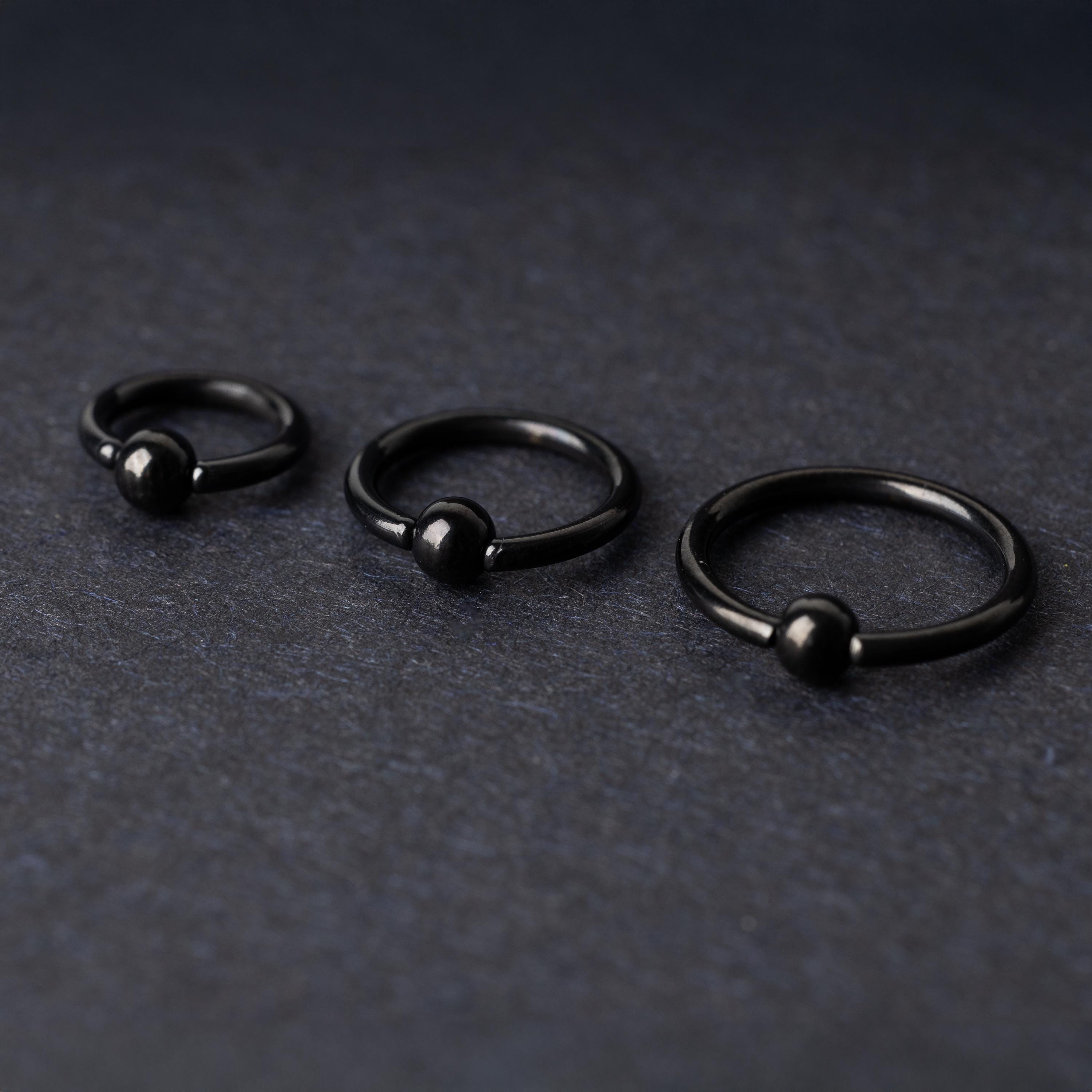 Three black ball closure rings (BCR) in varying sizes, displayed on a dark background with a polished finish and secure captive balls.