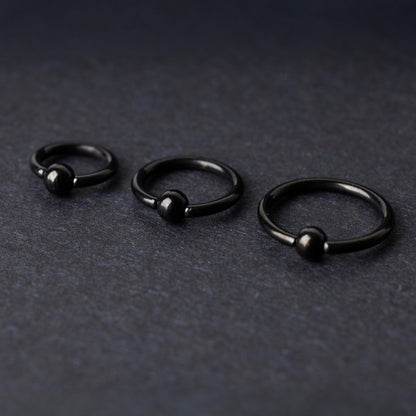 Three black ball closure rings (BCR) in varying sizes, displayed on a dark background with a polished finish and secure captive balls.