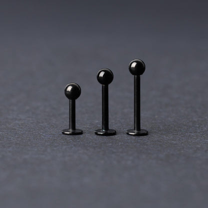 Three black stainless steel flat back barbells with polished finishes, displayed on a dark background.