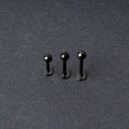 Three black stainless steel flat back barbells with polished finishes, displayed on a dark background.