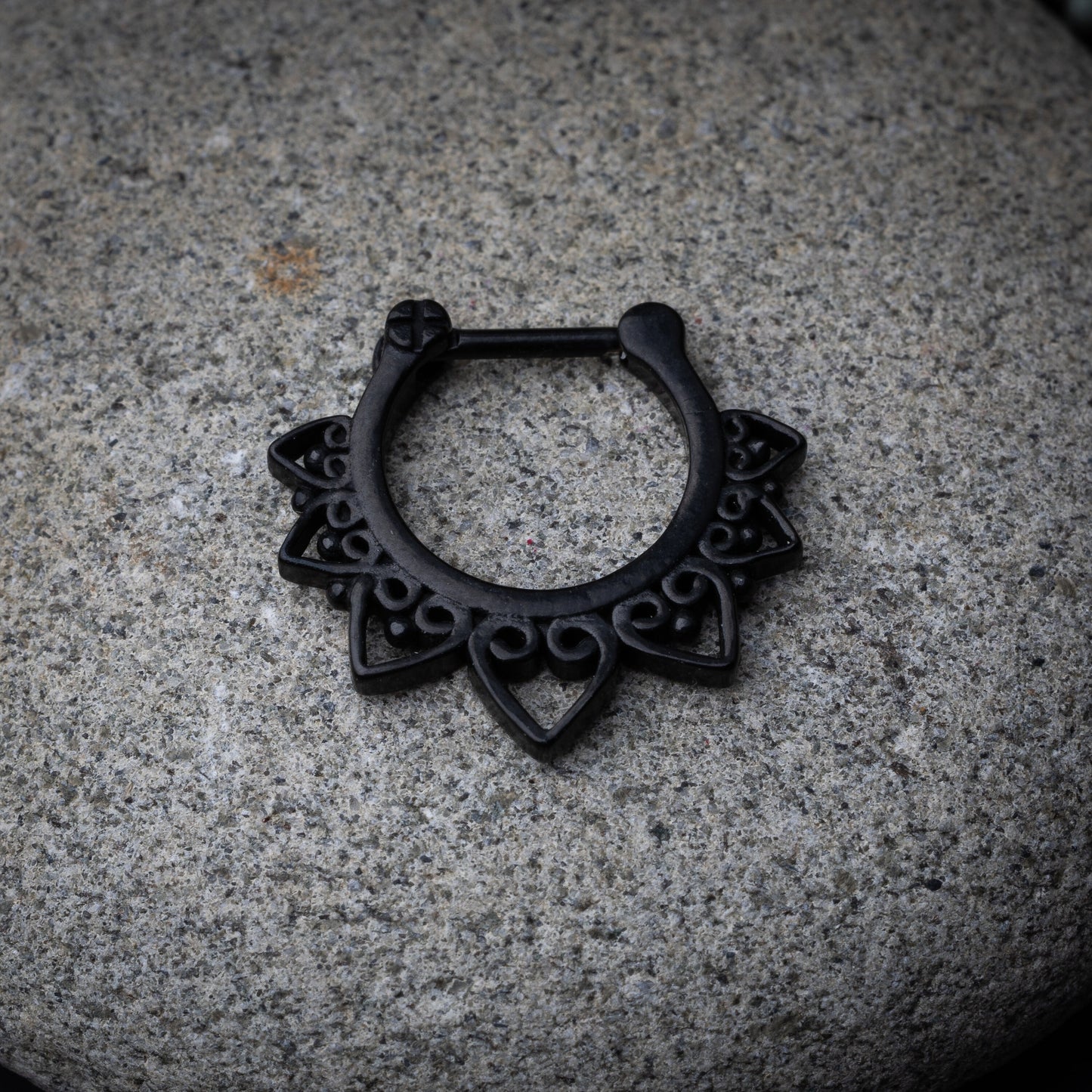 Black septum clicker with intricate geometric and swirl detailing.